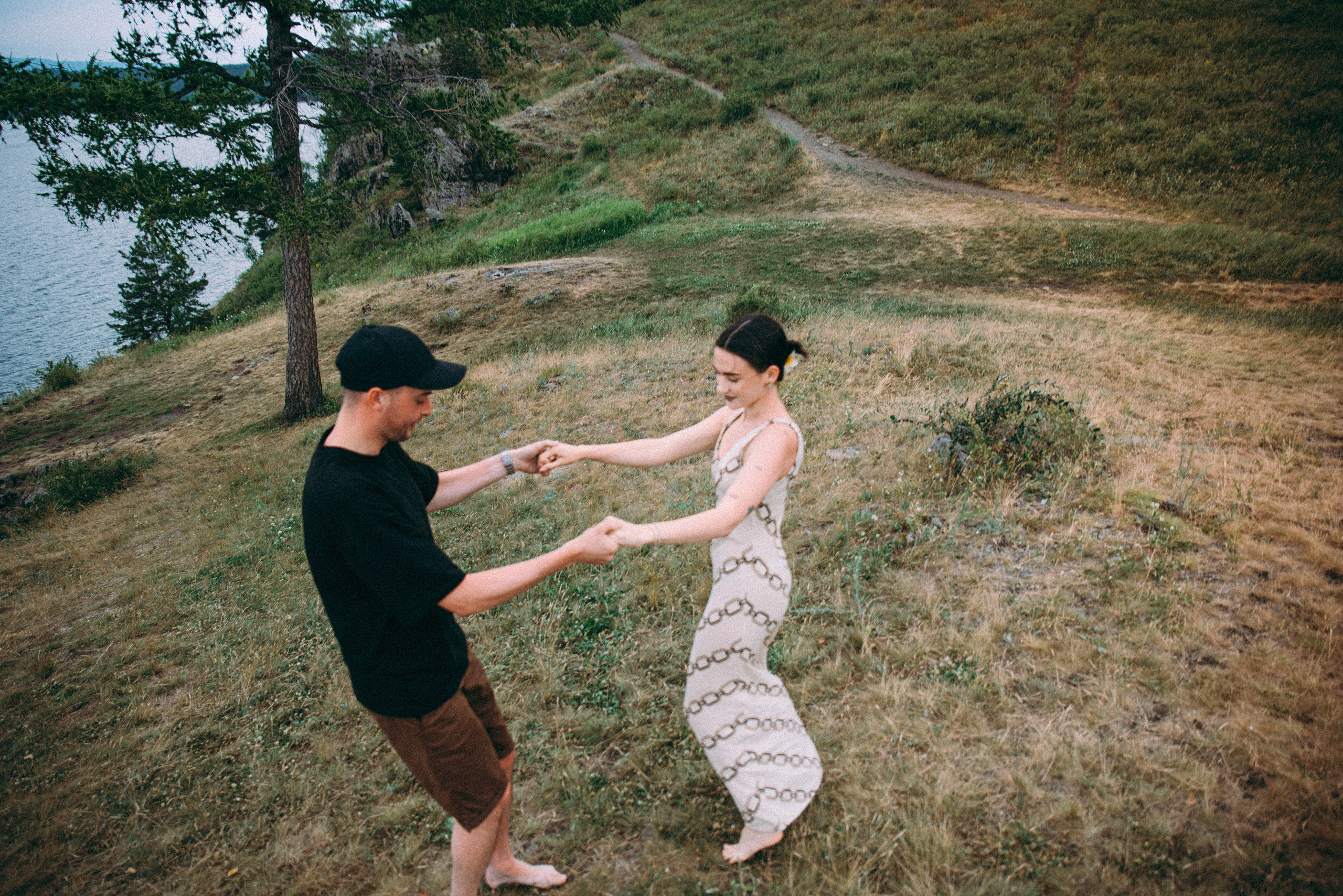 девушка и парень кружатся на берегу озера на съемках лавстори