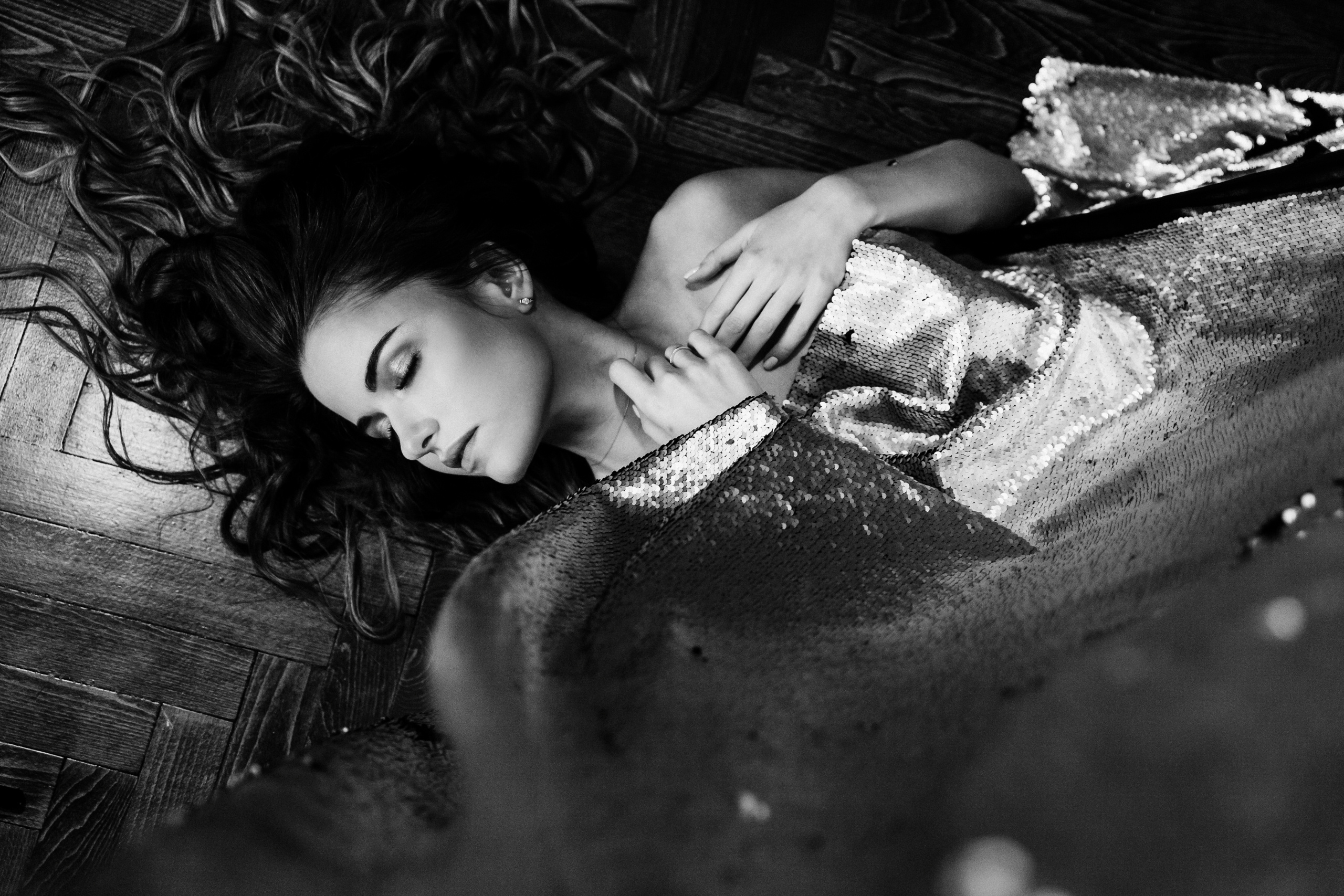 Красивая обнаженная девушка лежит на полу накрытая тканью с блестками