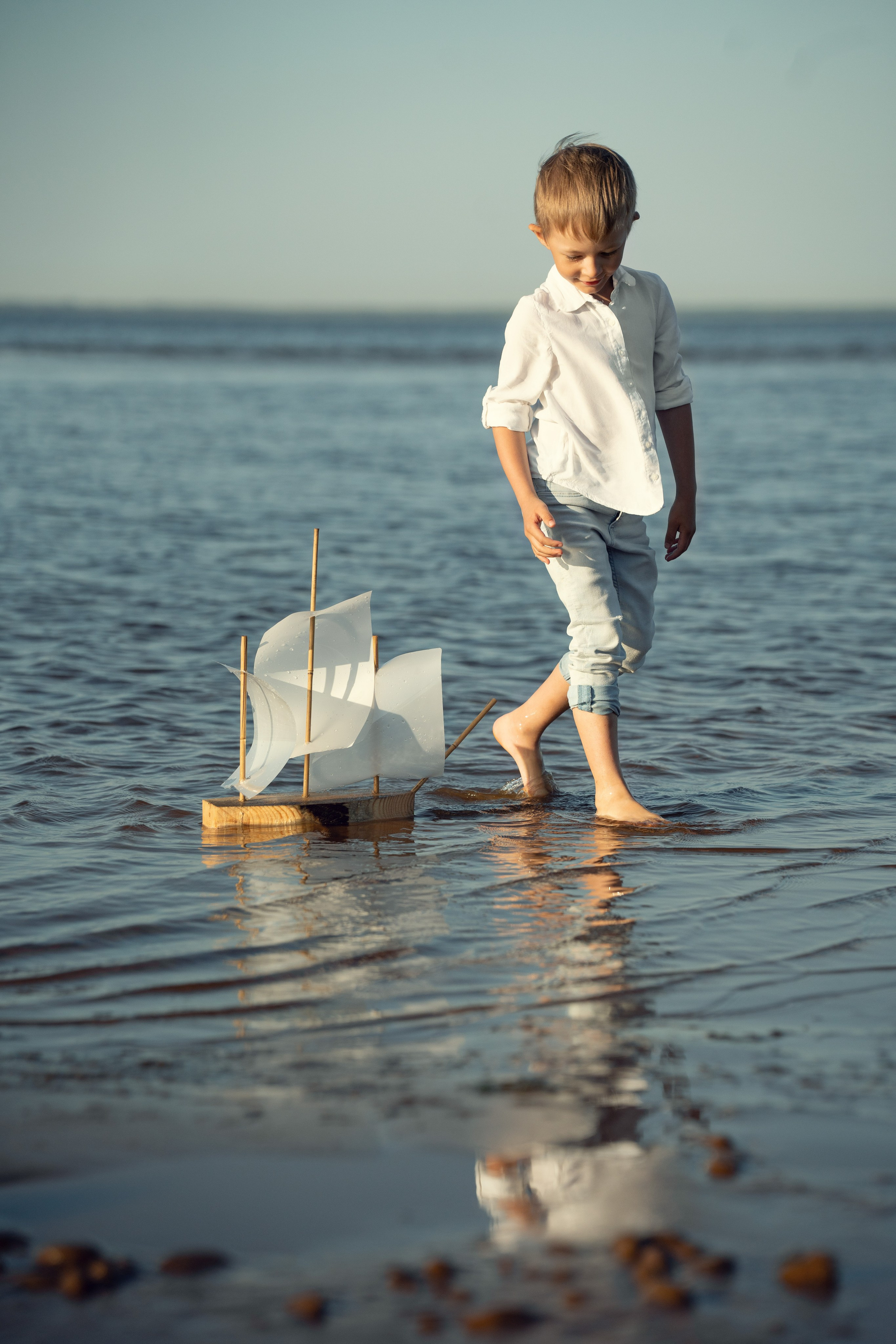 Мальчик на берегу Финского залива играет с корабликом.