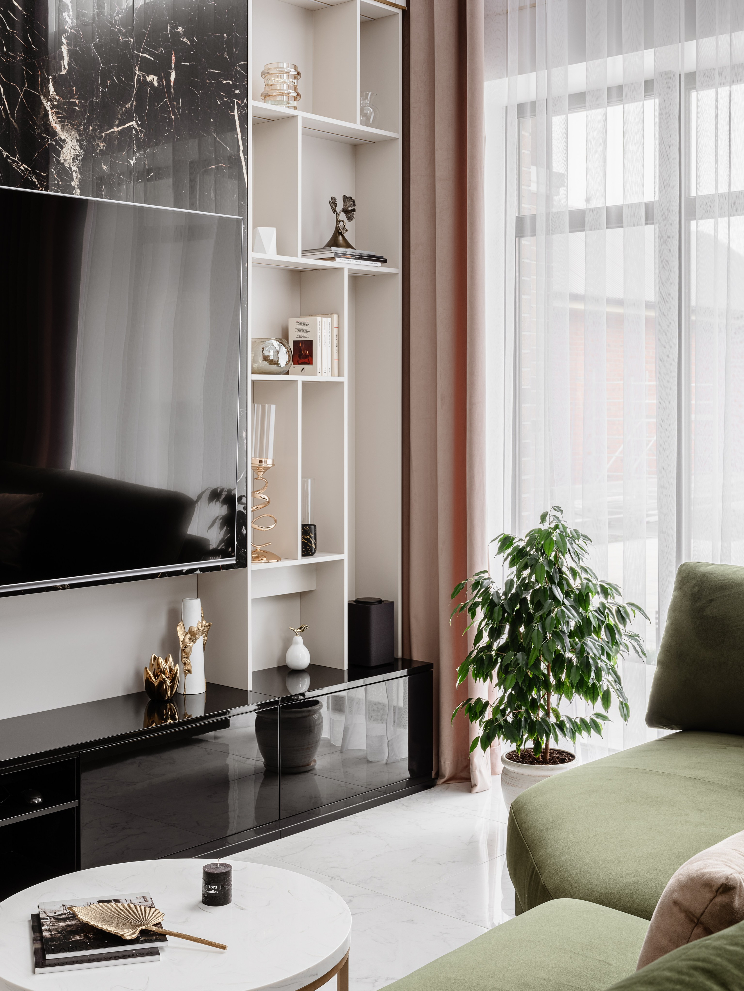Телевизионная зона гостиной с черным мраморным акцентом и белыми стеллажами, зеленый диван и стильный декор создают уют, интерьер разработан Евгенией Ермошиной, фотограф Сергей Денисенко.