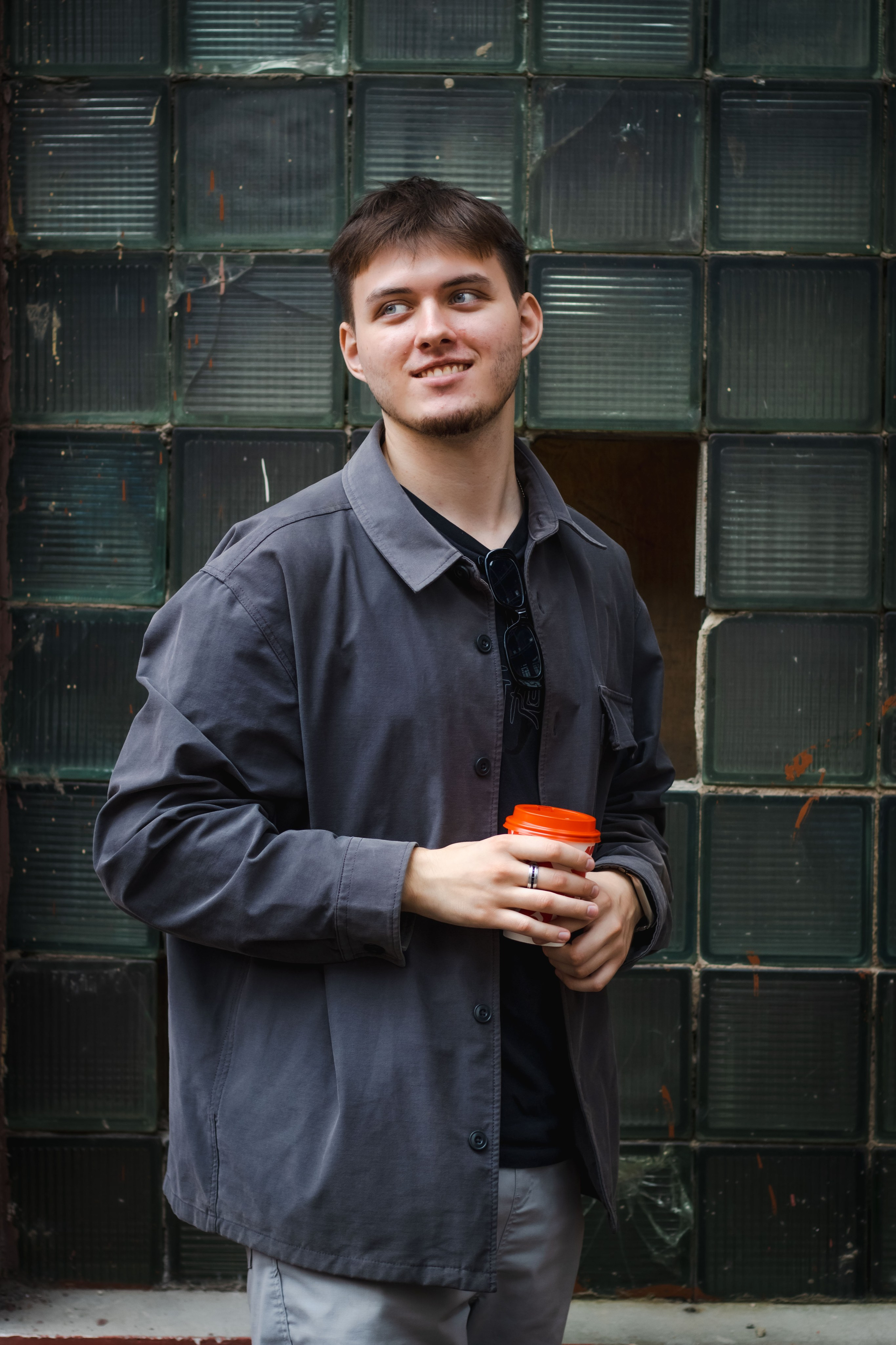 парень со стаканом кофе с собой, гуляет по улице