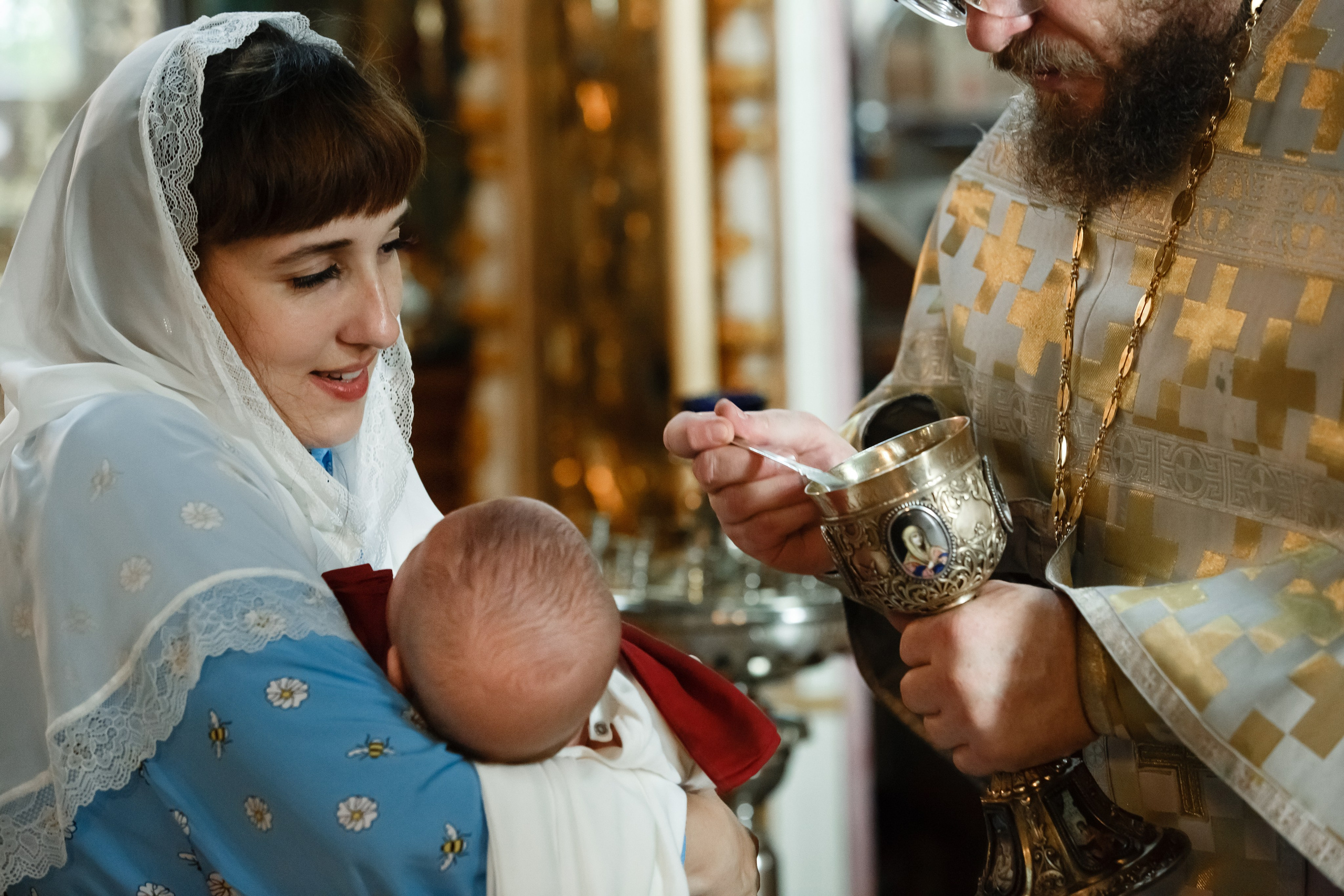 батюшка причащает малыша