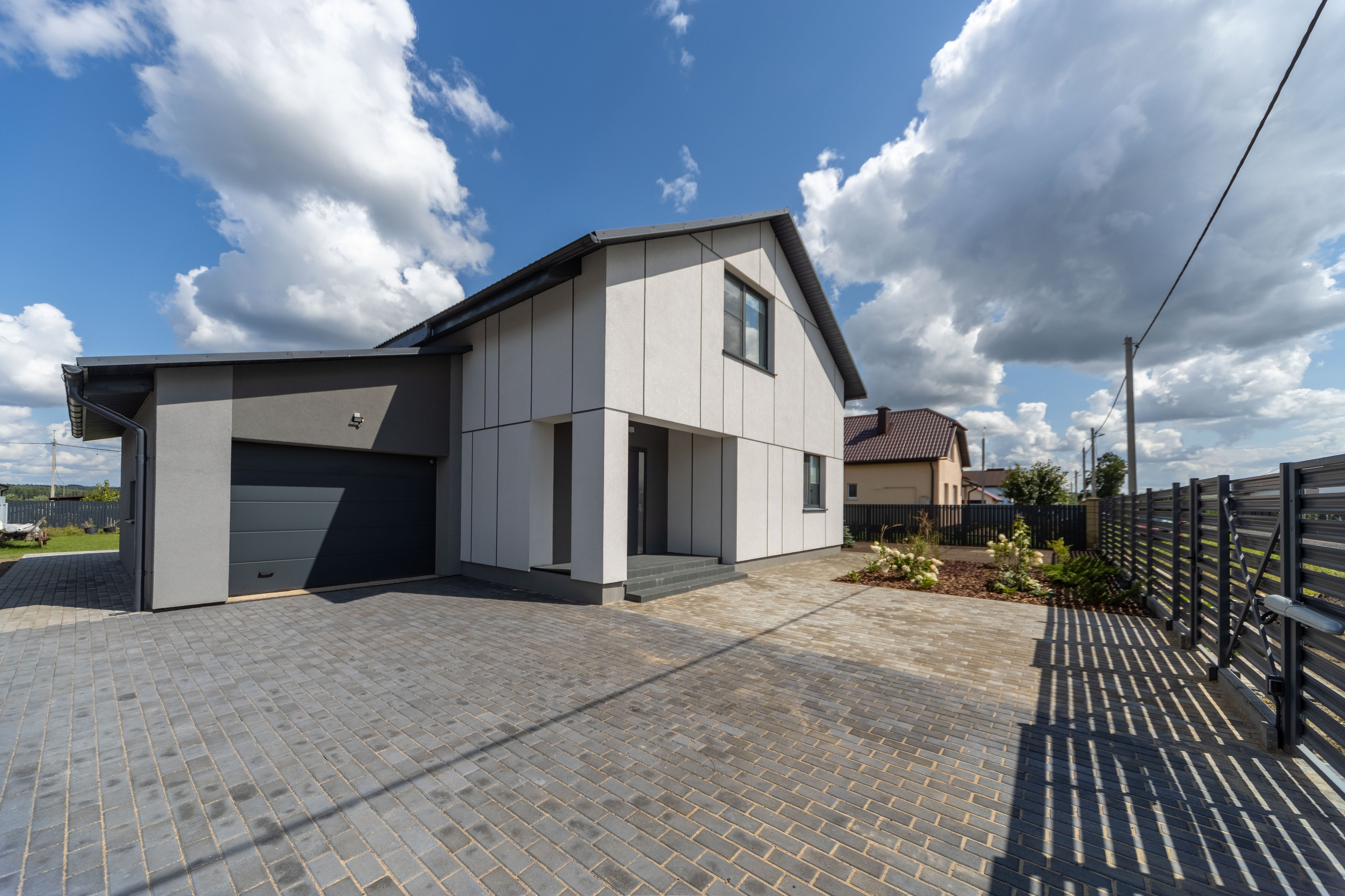 Двухэтажный коттедж в гаражом в солнечную погоду летом