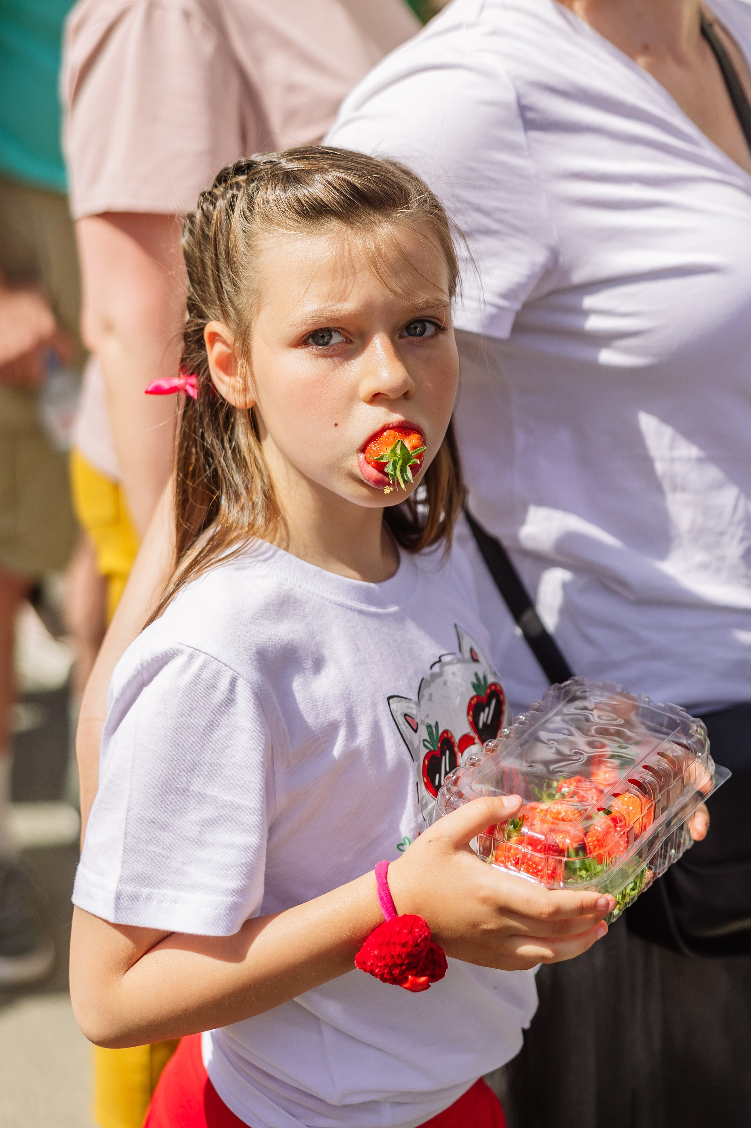 Фотография девочки, которая держит клубнику во рту