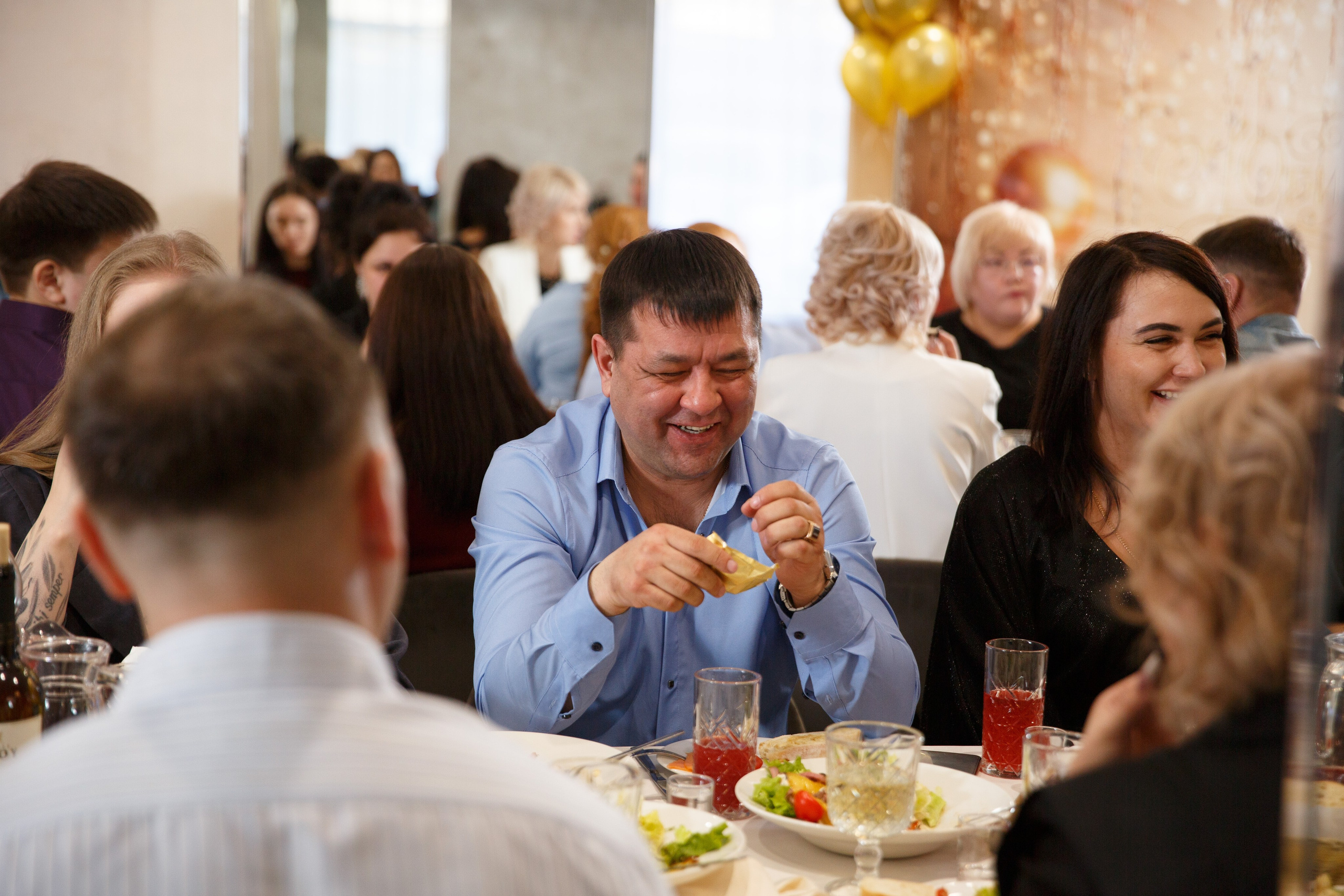 Гость смеется  за праздничным столом, светская беседа и радость встречи.