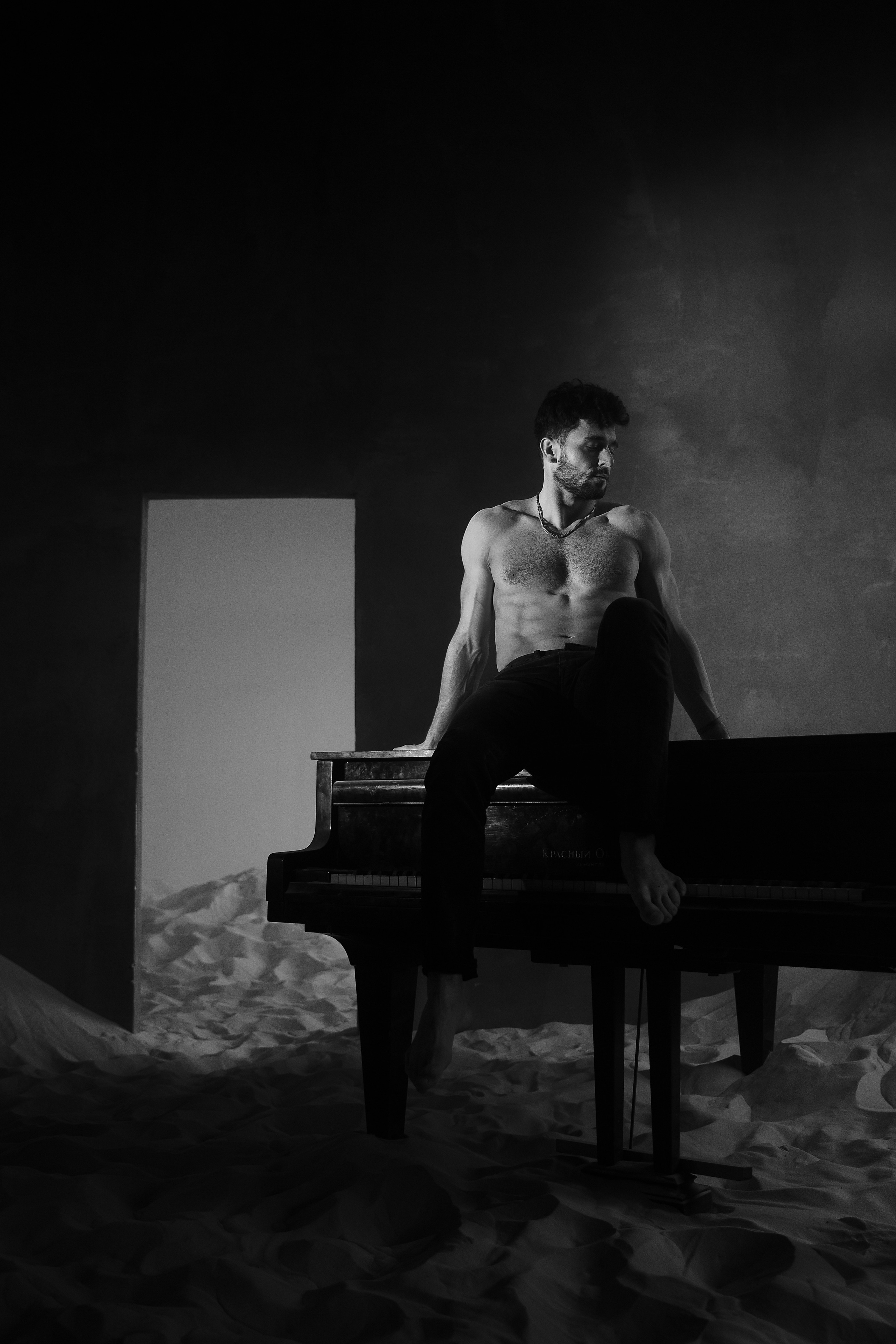 Мужчина сидит на рояле в комнате
