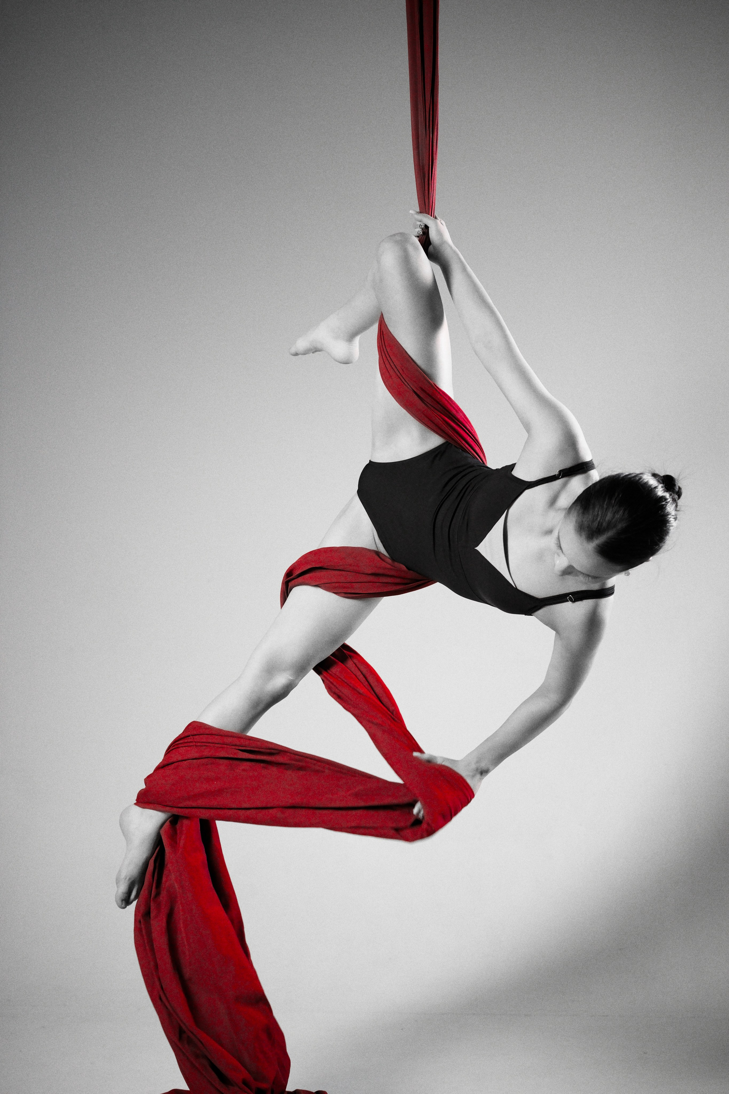 Художественная фиксация сложного элемента на воздушных полотнах, динамичная поза гимнастки в полный рост