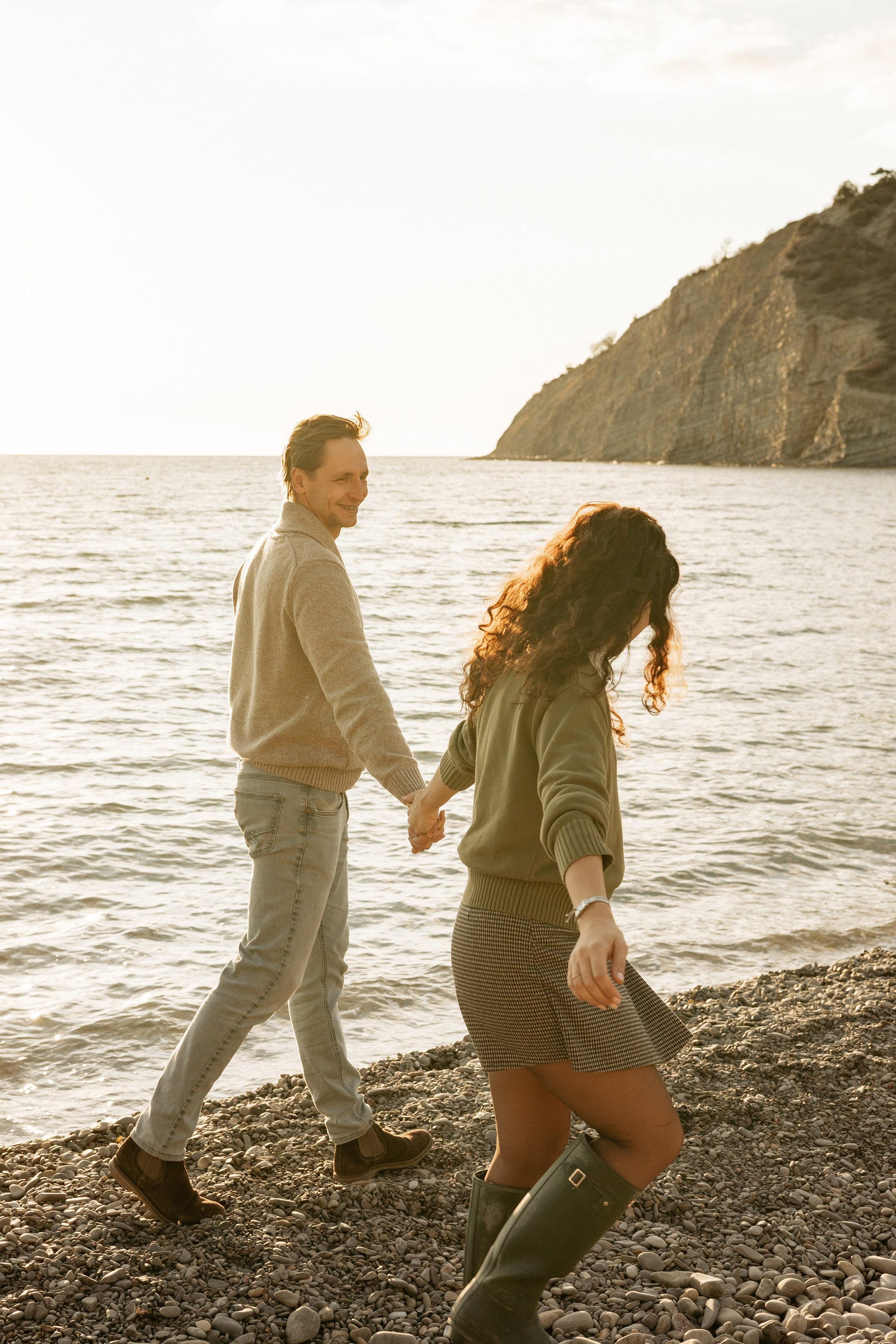 Семейная пара идут по берегу моря за руки