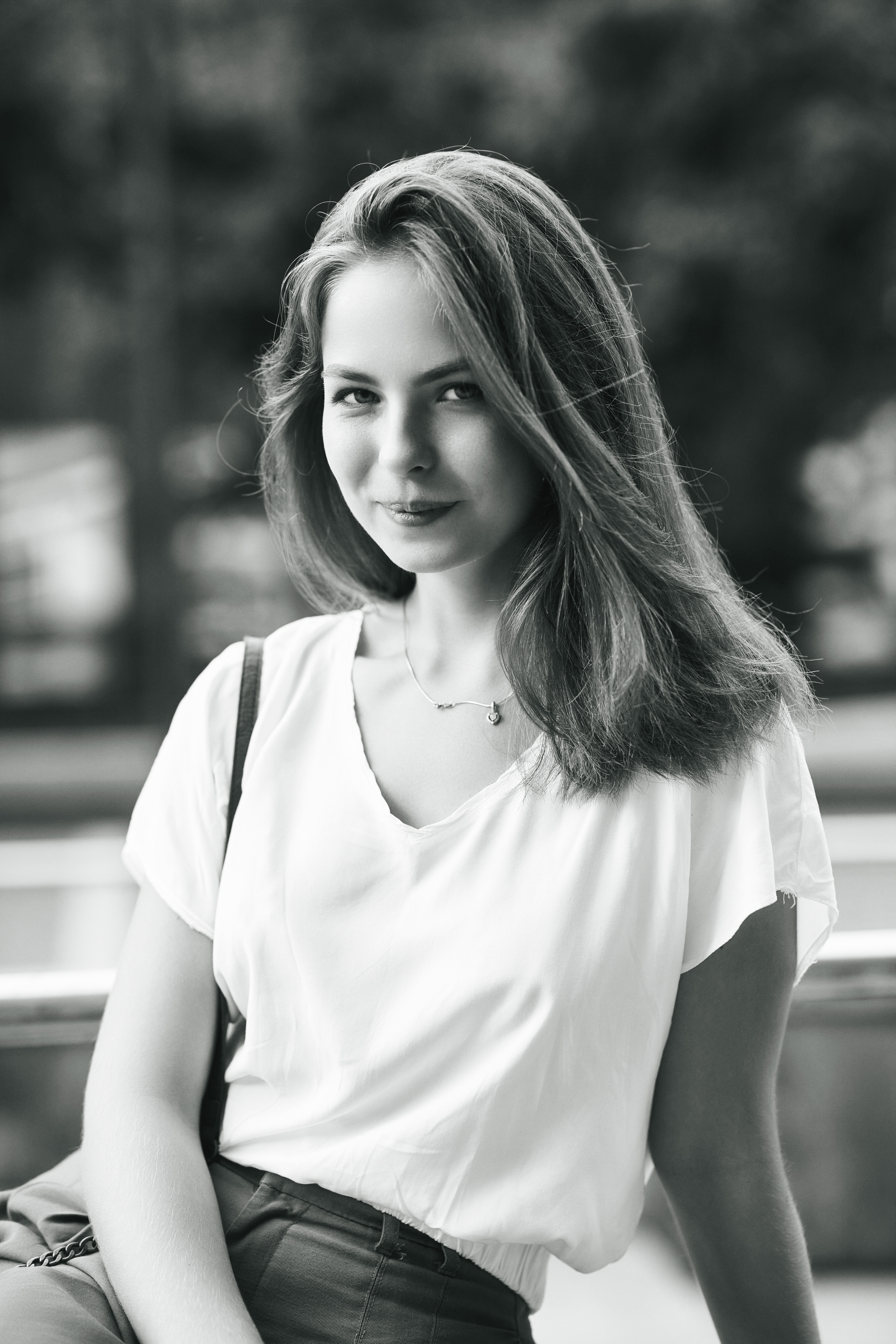 Дарья на улице города в светлой кофте и с густыми темными волосами