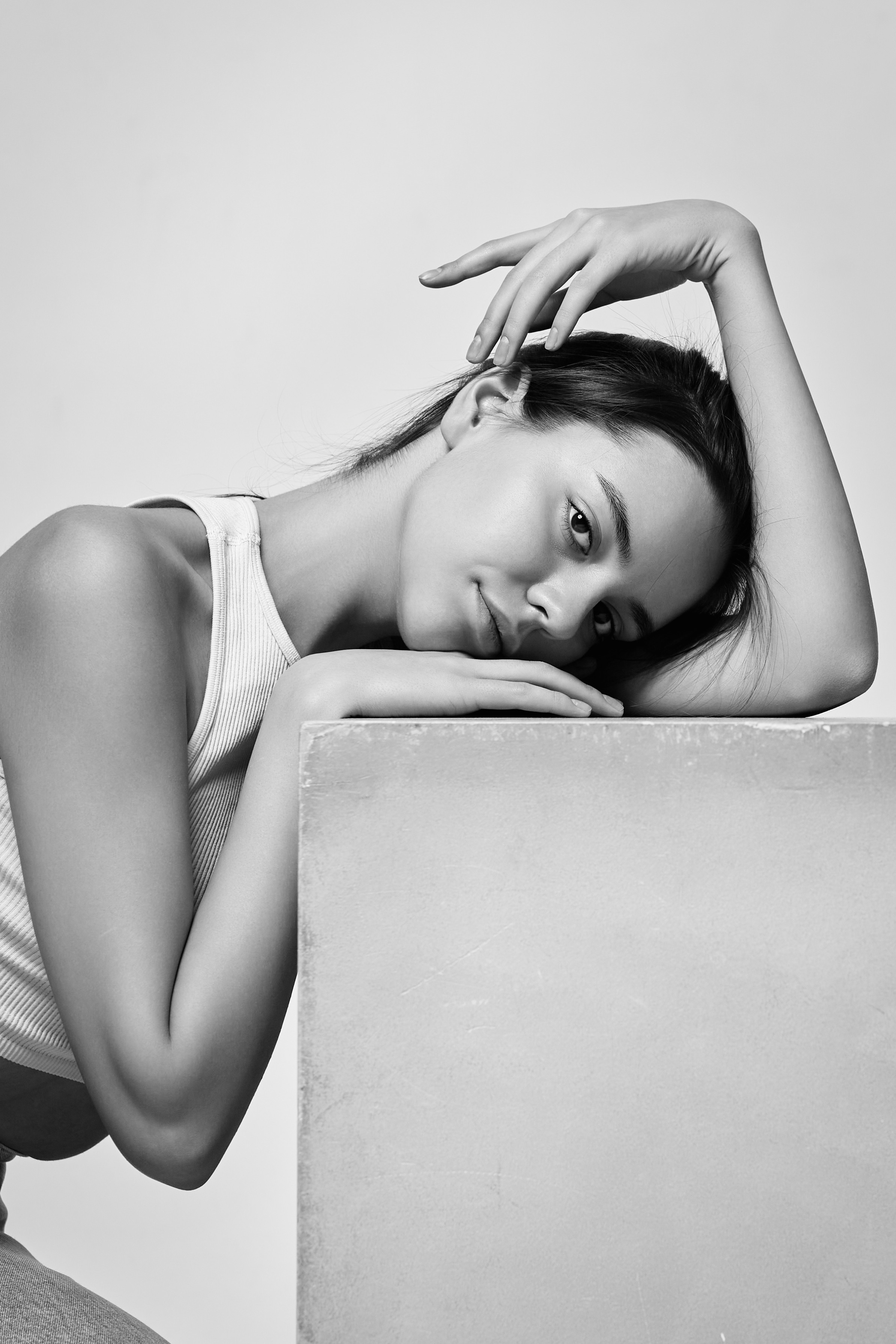 Взгляд темноволосой модели Амины в светлом платье на светлом фоне в студии