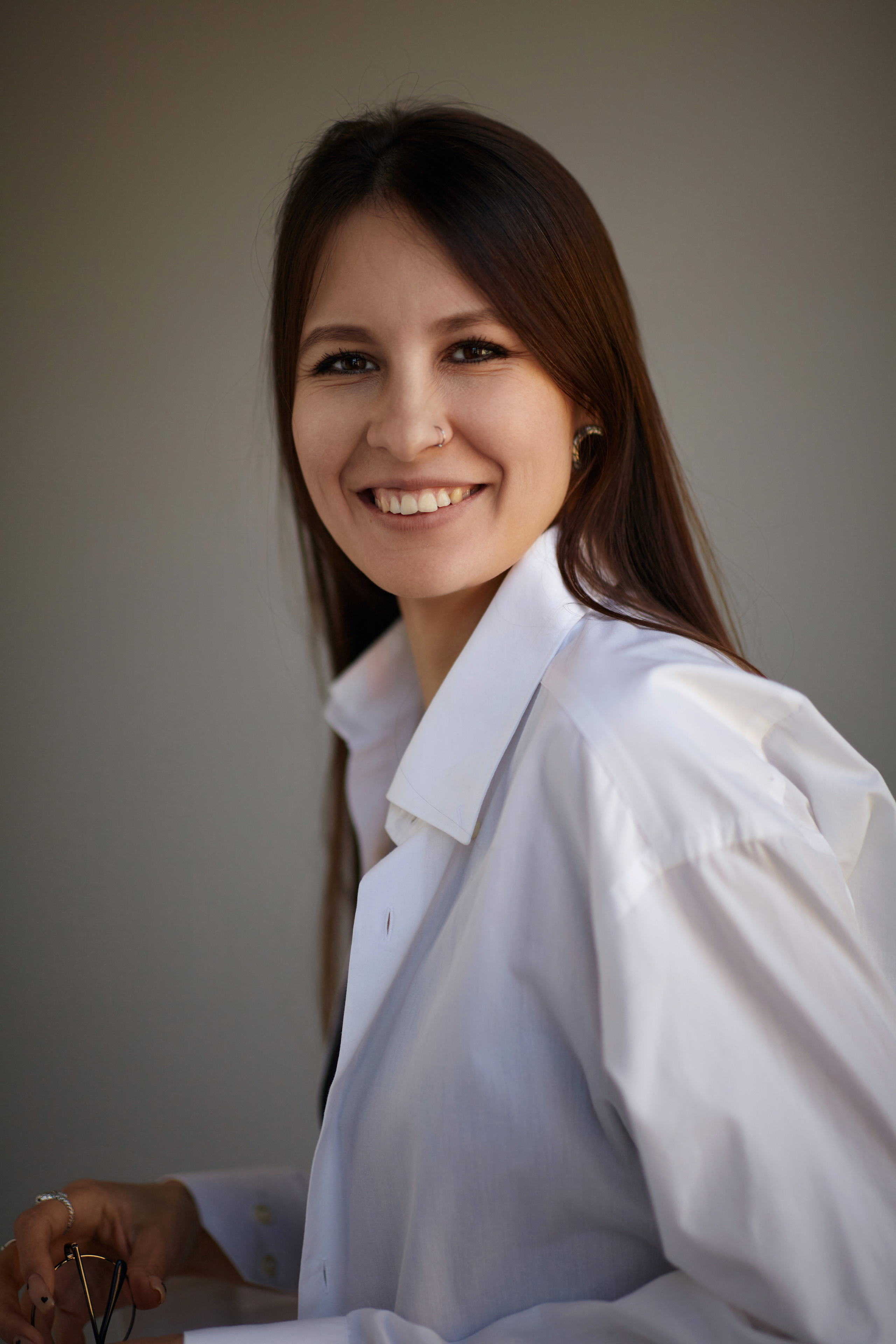 Темноволосая модель на темном фоне циклорамы в студии позирует перед камерой.