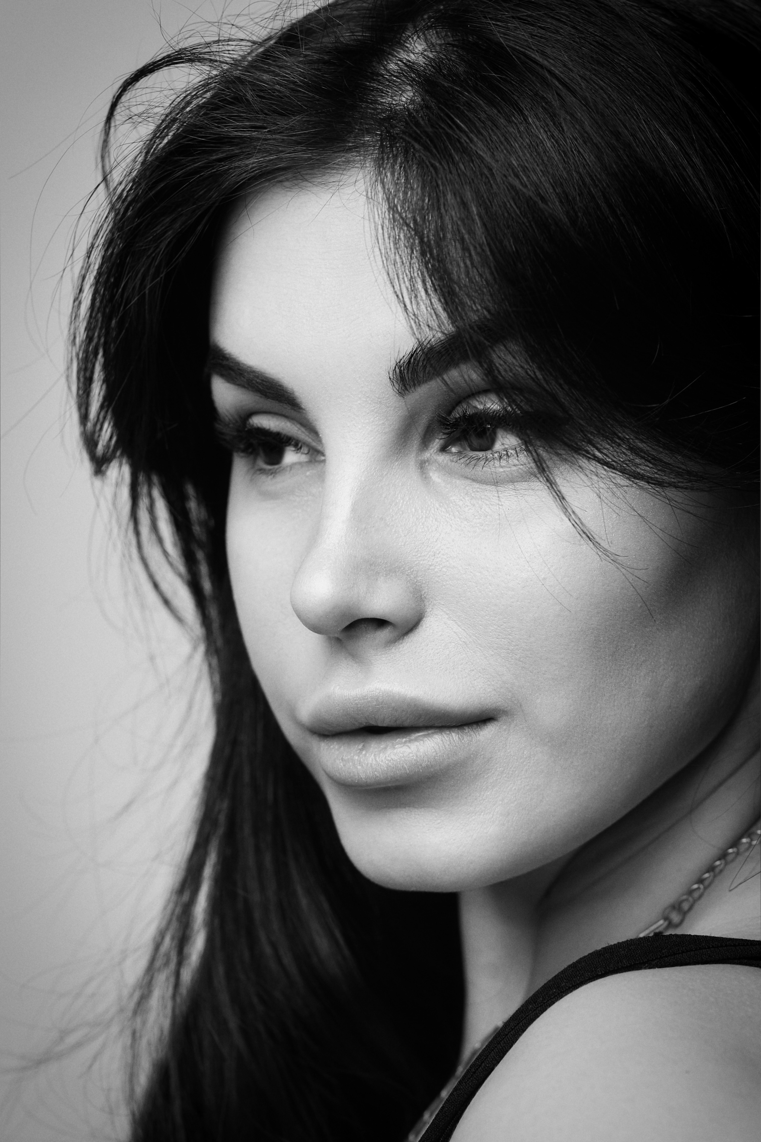 Темноволосая модель Карина в рубашке на светлом фоне студии создает образ деловой женщины, умеющей добиваться своих целей.