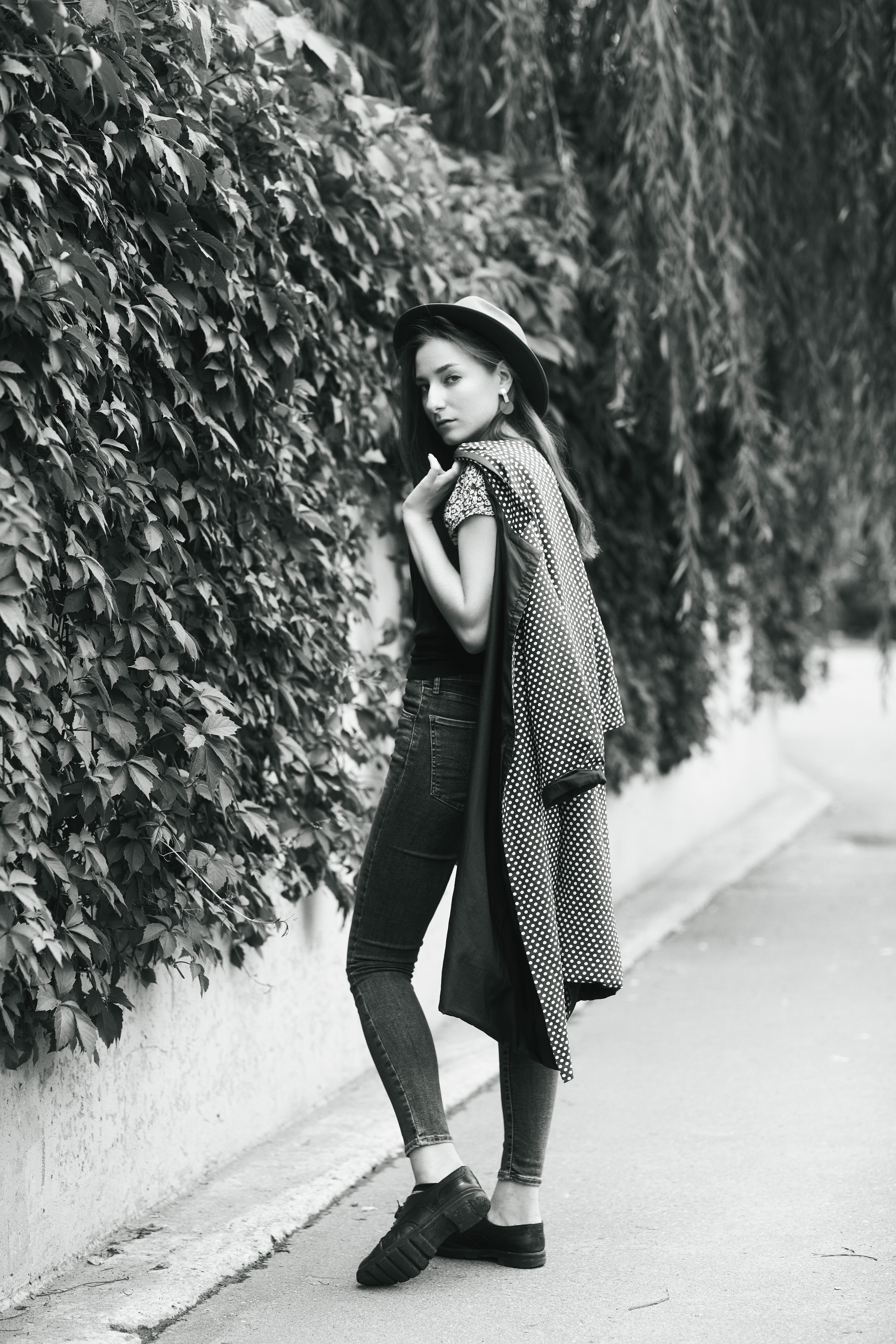 Темноволосая красавица Любовь на улице в городе, облаченная в прекрасное платье, которое подчеркивает ее изящную фигуру.