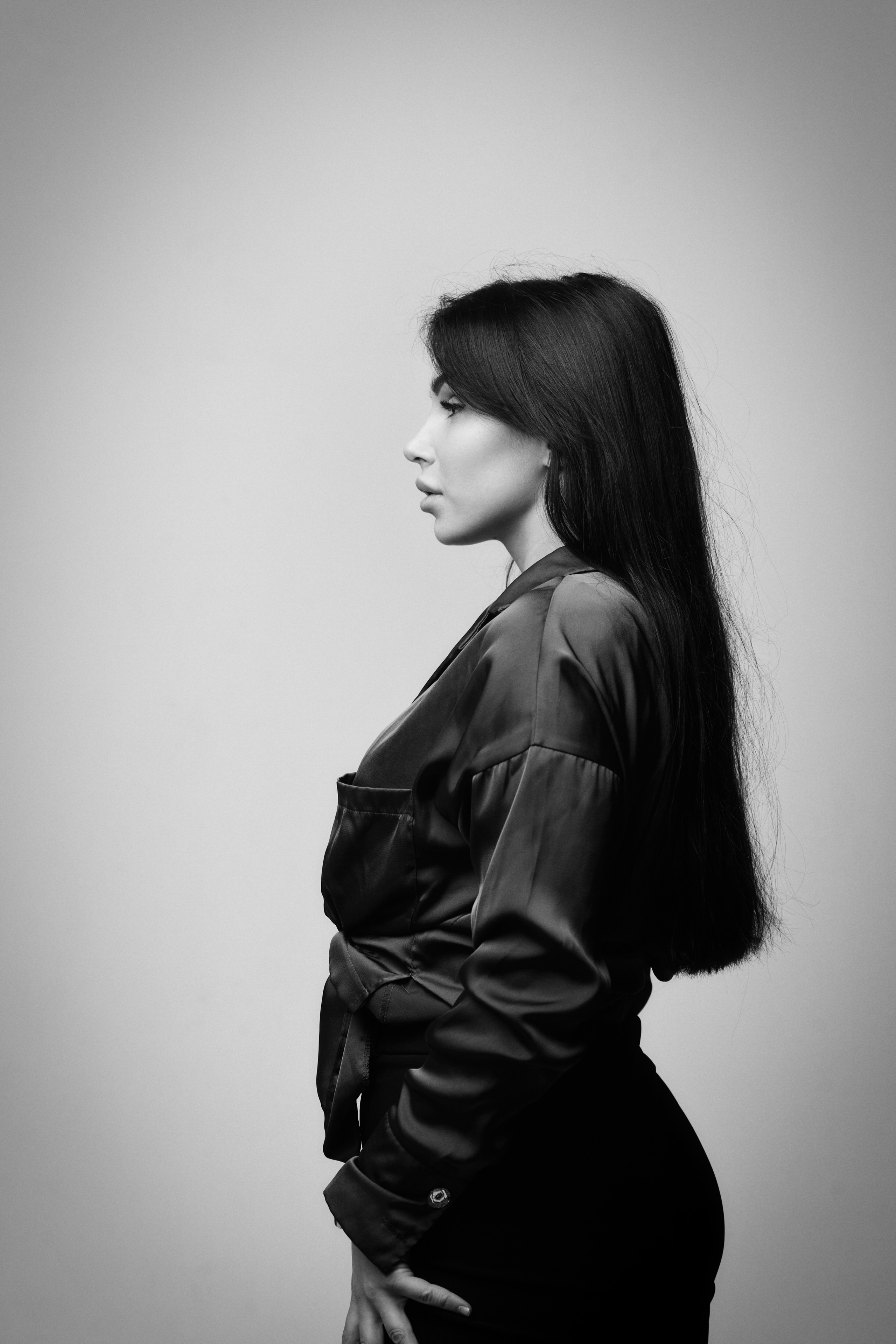 Темноволосая модель Карина в платье на светлом фоне в студии.