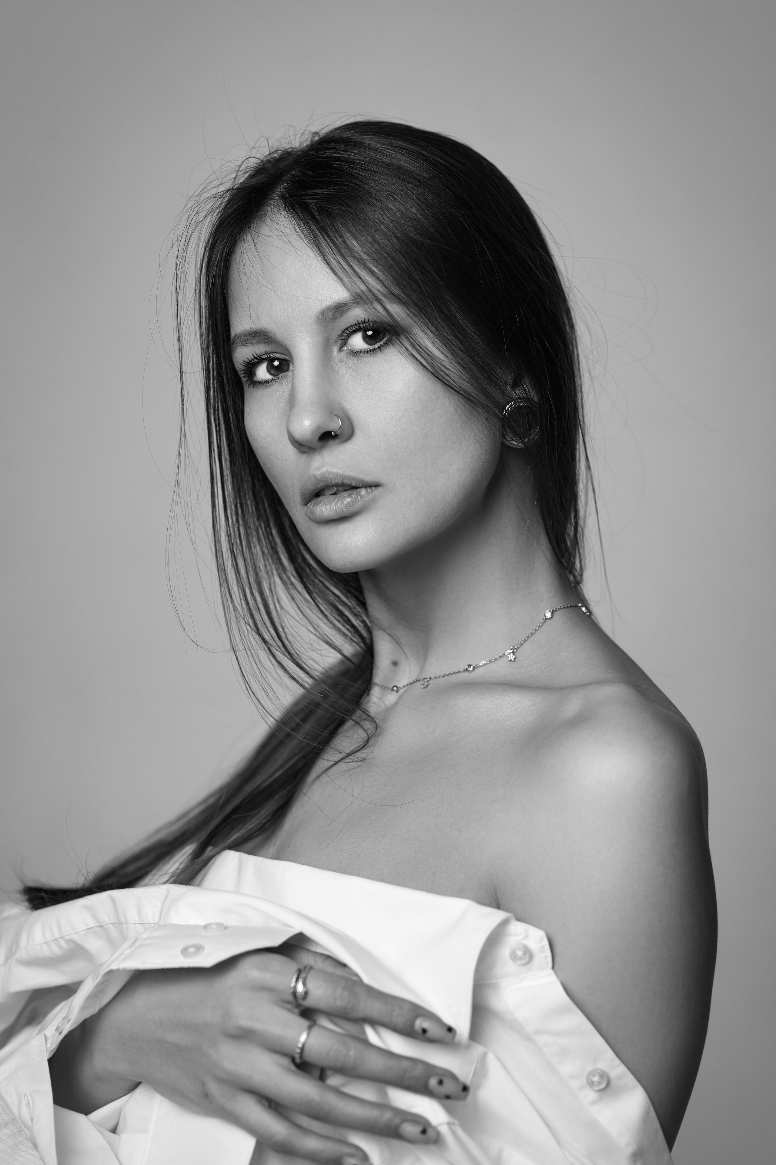 Темноволосая модель в фотостудии на темном фоне с элегантной одеждой