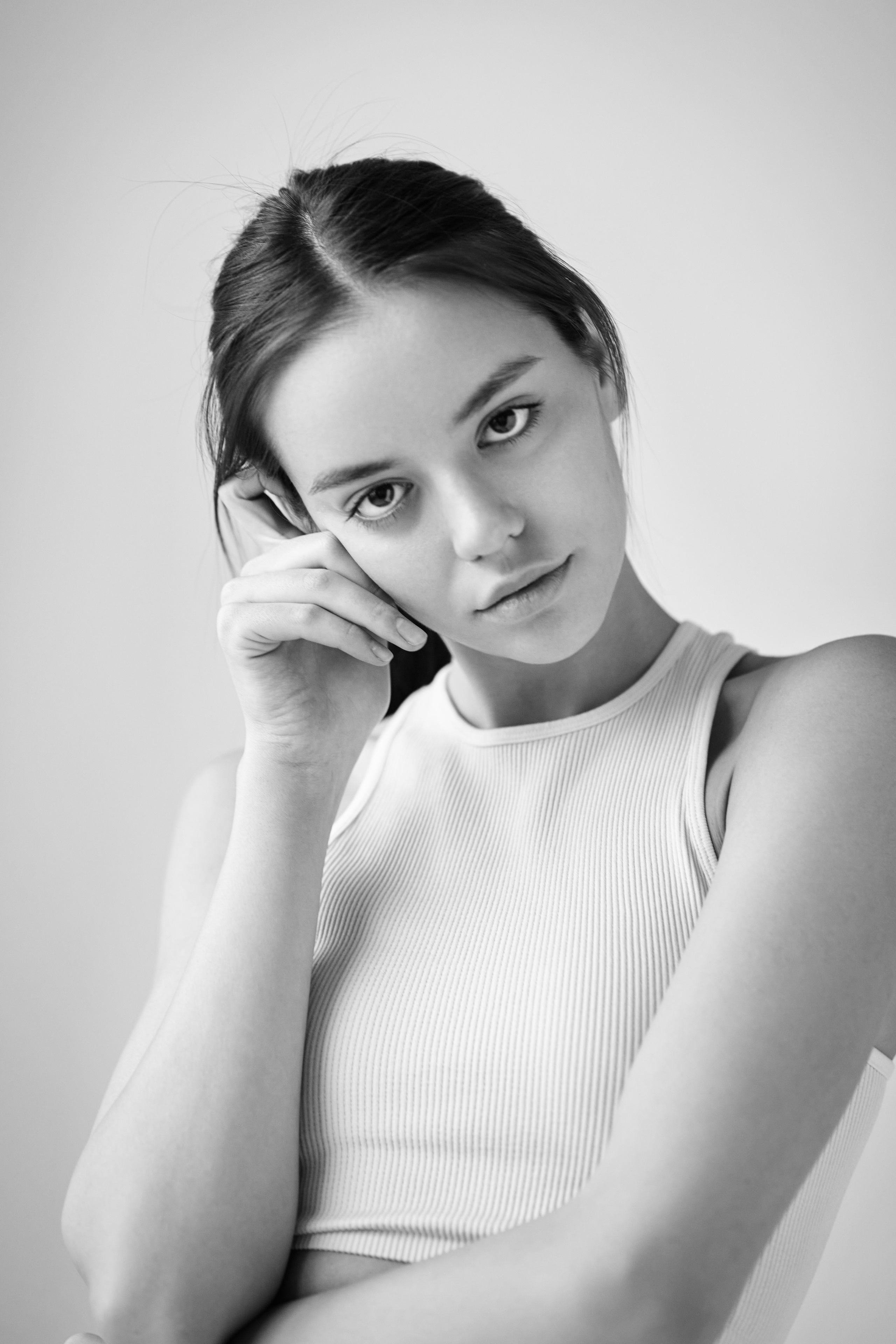 Темноволосая красотка Амина на светлом фоне в белом платье с открытыми плечами.