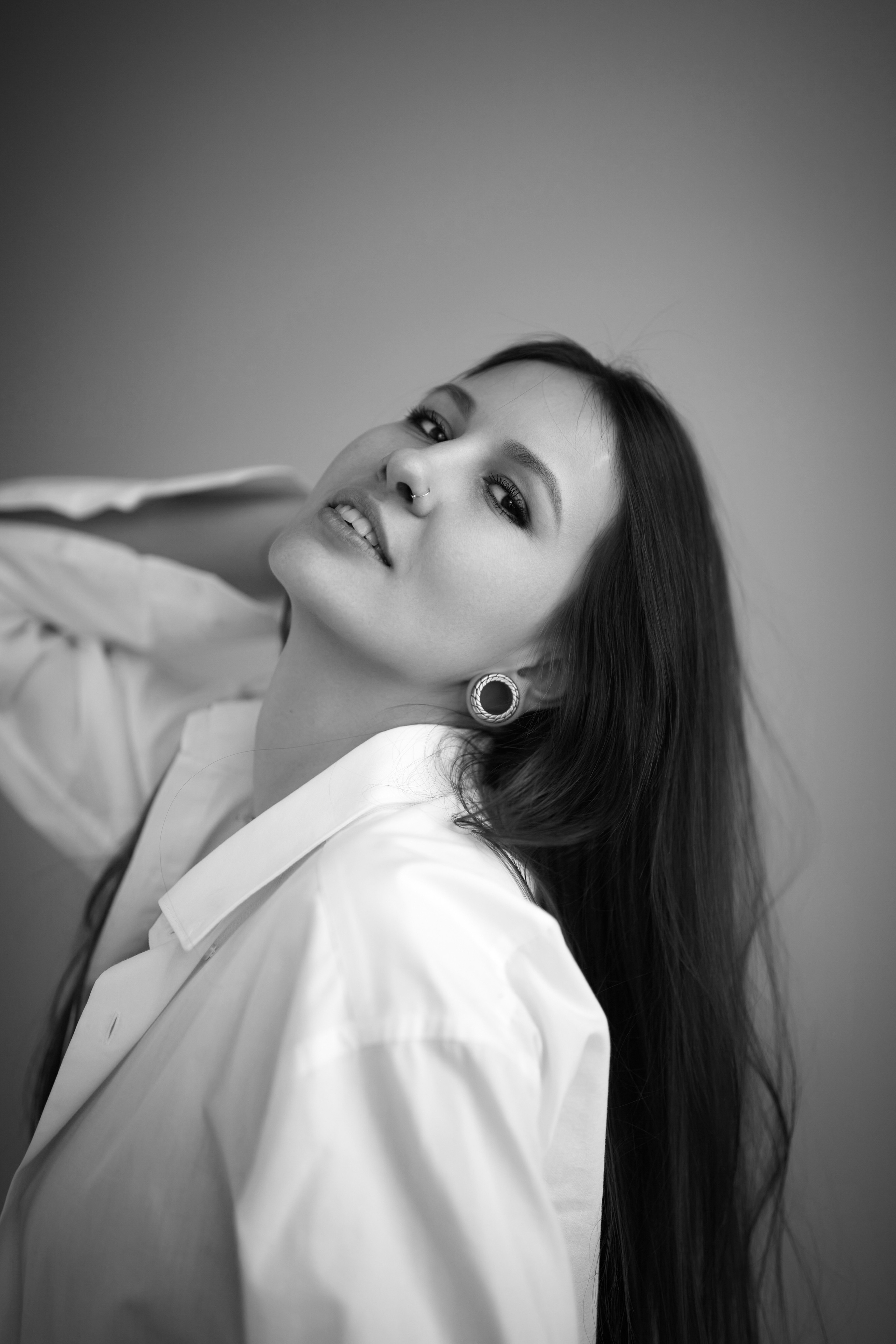 На фоне циклорамы с темным фоном в студии стоит темноволосая красавица.