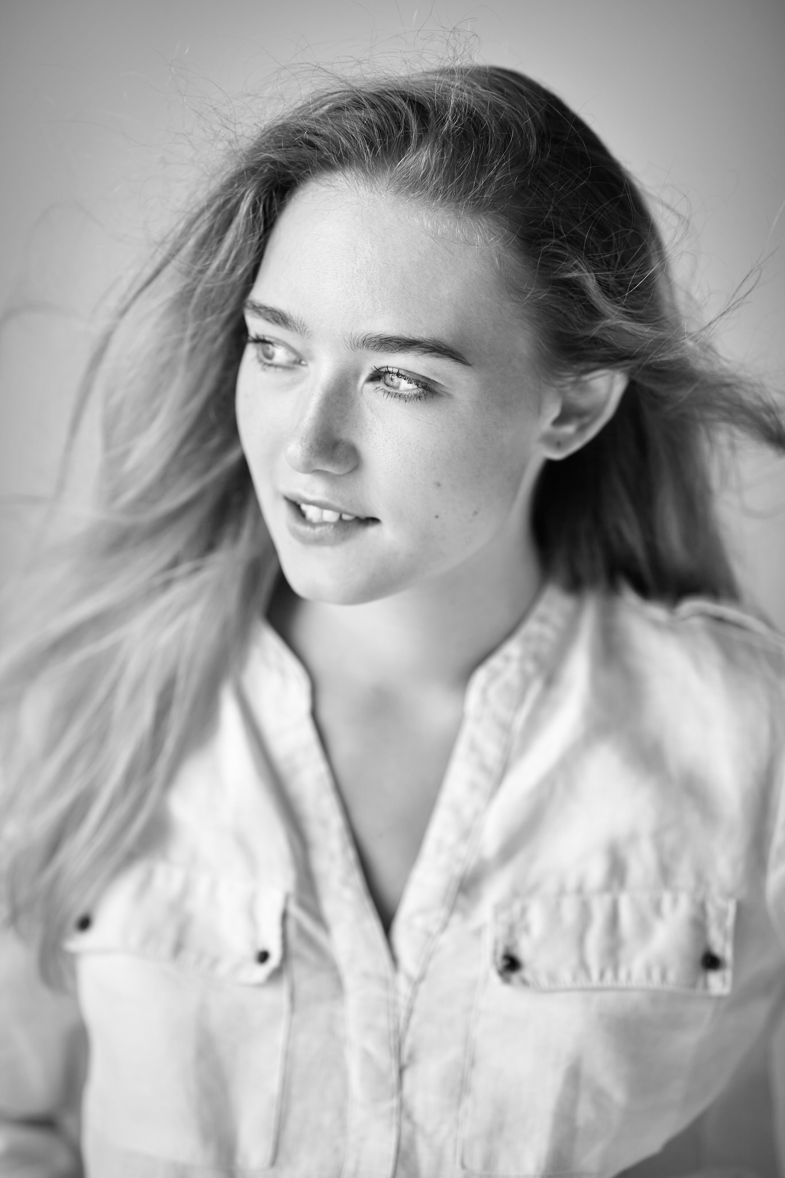 План на голову светловолосой модели Алисы в студии на светлом фоне, облаченной в гламурное платье.