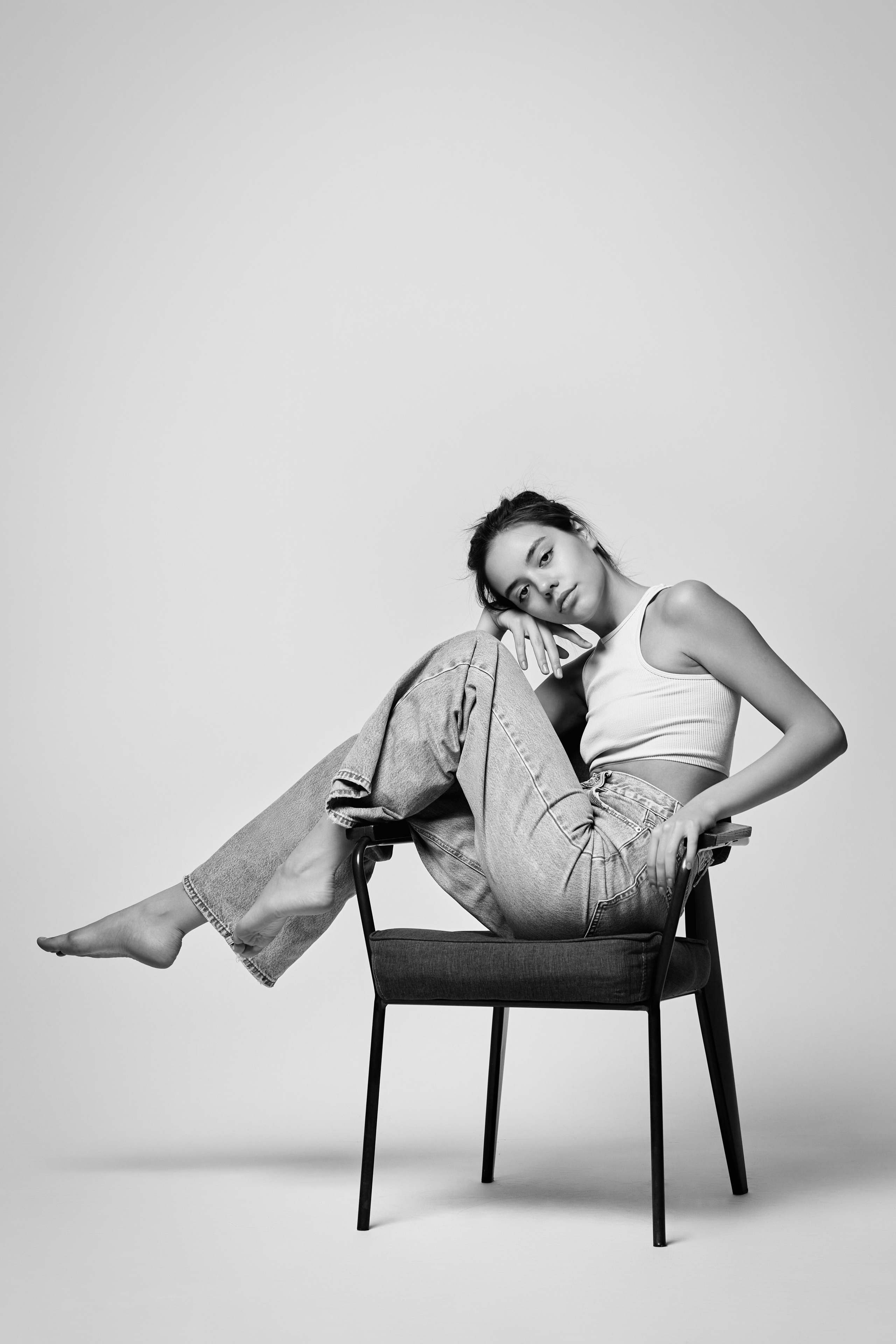 Темноволосая Амина на светлом фоне в студии одета в рубашку, ее губы ярко выделены помадой.