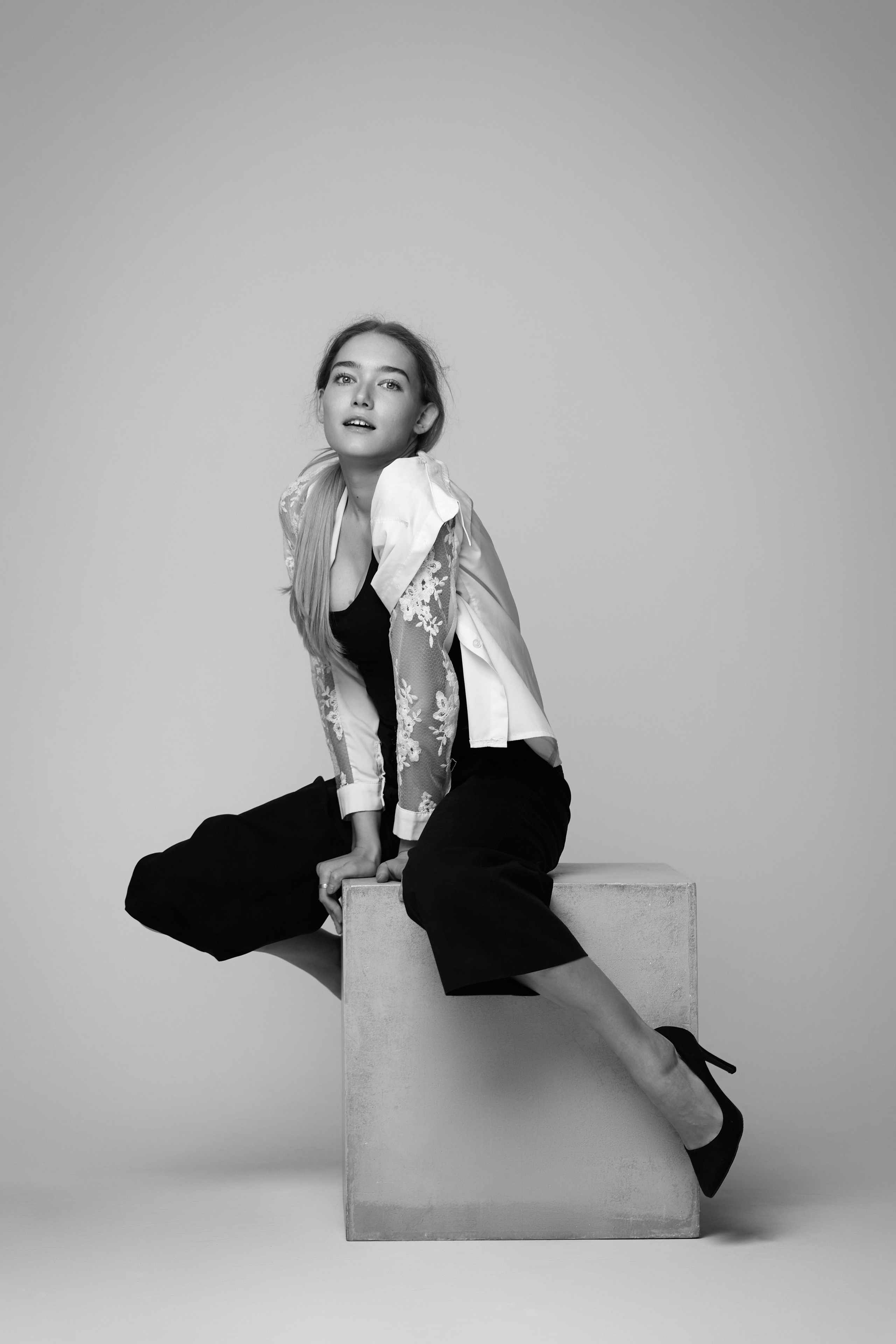 Алиса, модель с шикарными волосами, воплощает образ в студии на светлом фоне, представив себя в платье или рубашке.