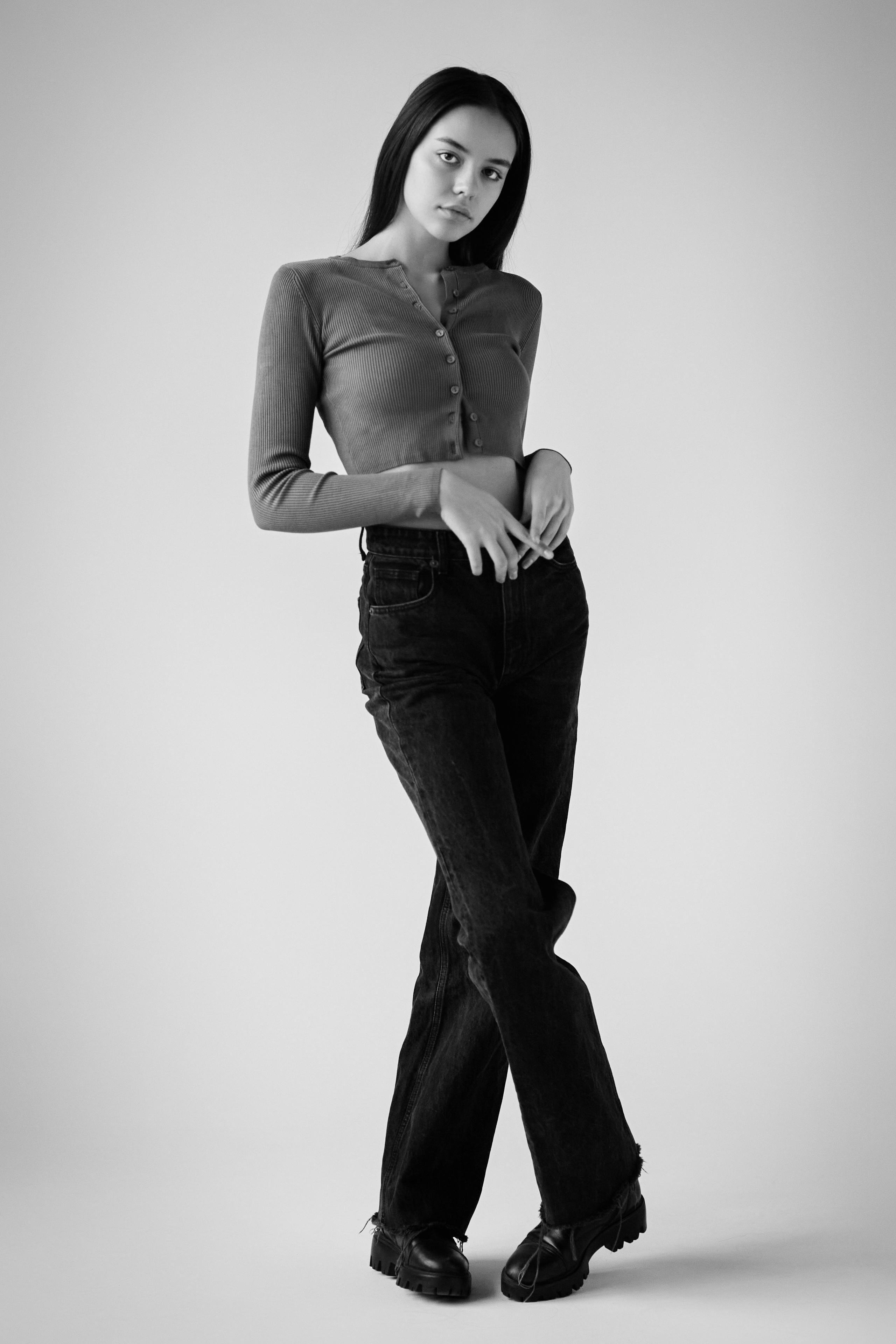 Темноволосая Амина на светлом фоне в рубашке в студии создает элегантный образ