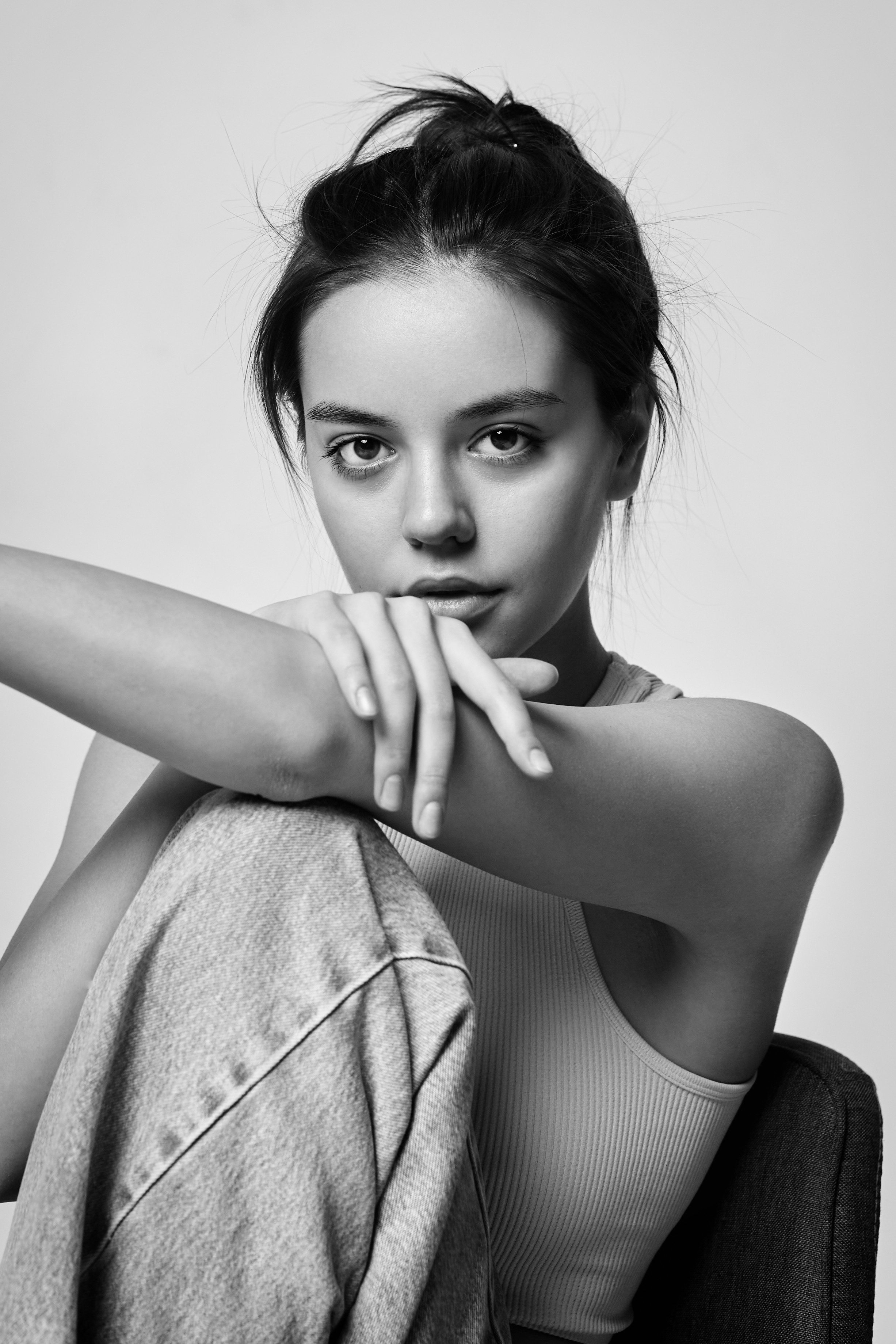 На светлом фоне в студии стоит темноволосая модель Амина, одетая в рубашку, у нее яркий макияж на глазах.