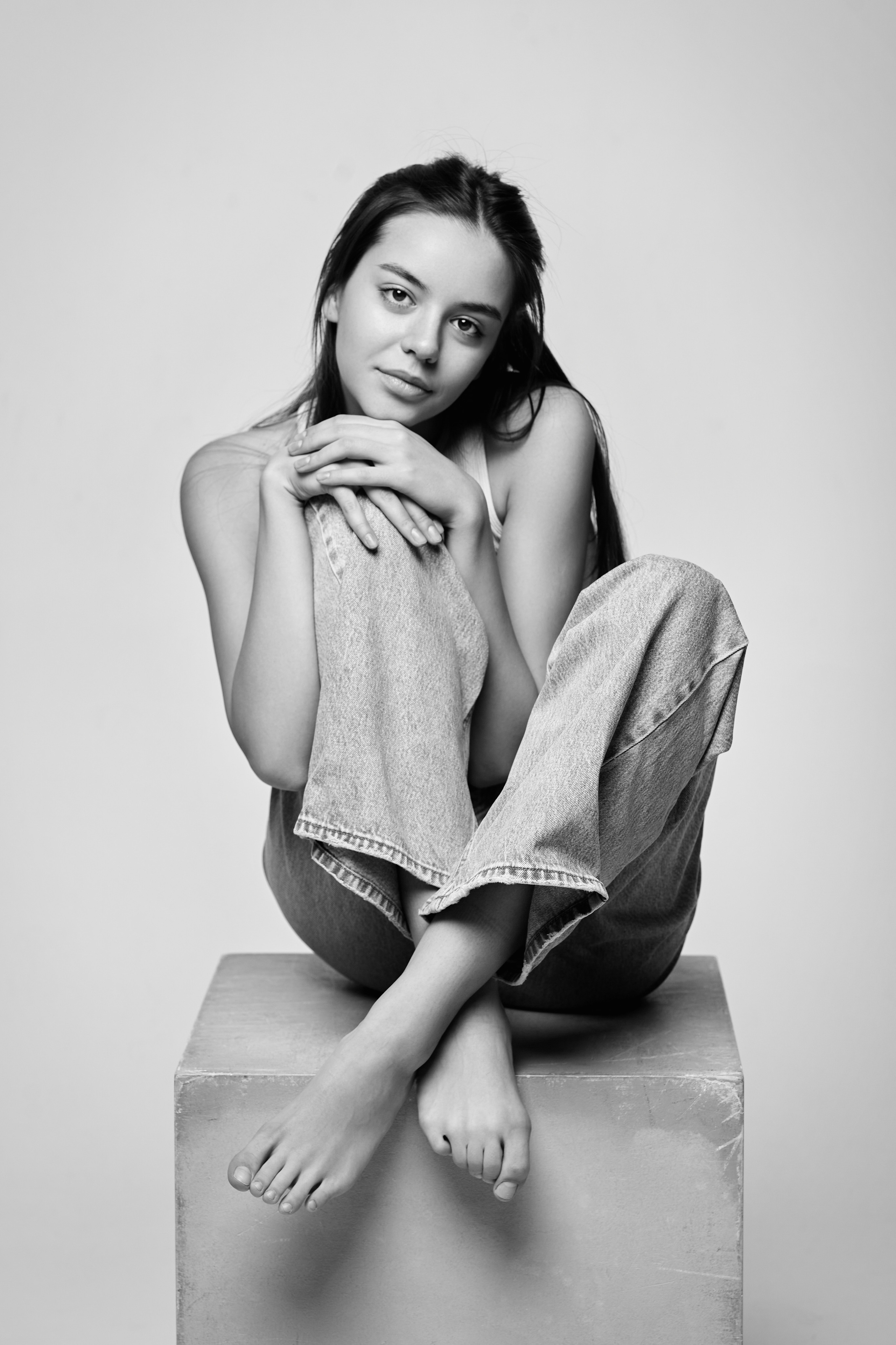 На светлом фоне темноволосая модель Амина выглядит утонченно в светлом платье.