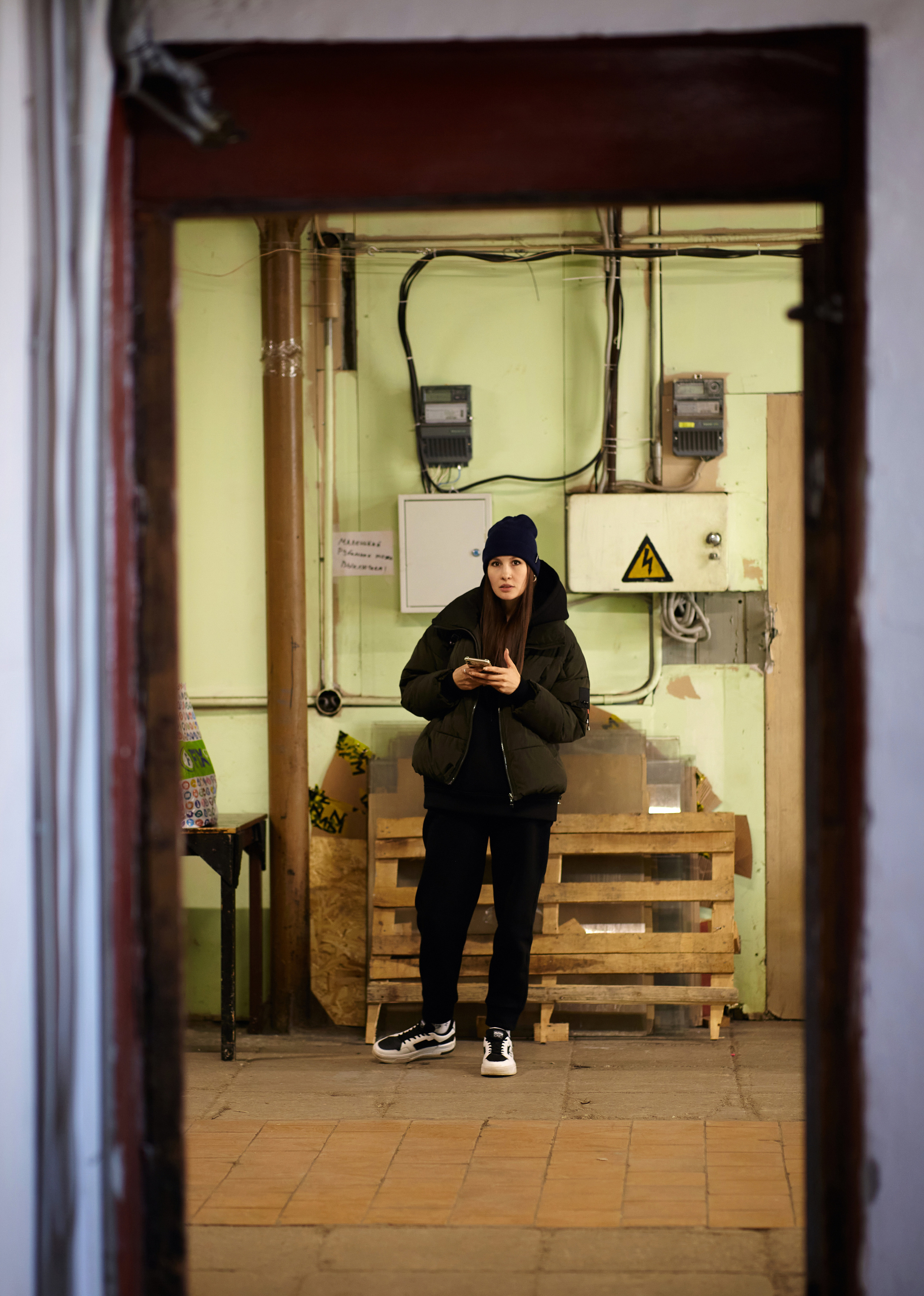 Изящная темноволосая девушка смотрит прямо в камеру, находясь в студии на светлом фоне, создавая элегантный образ