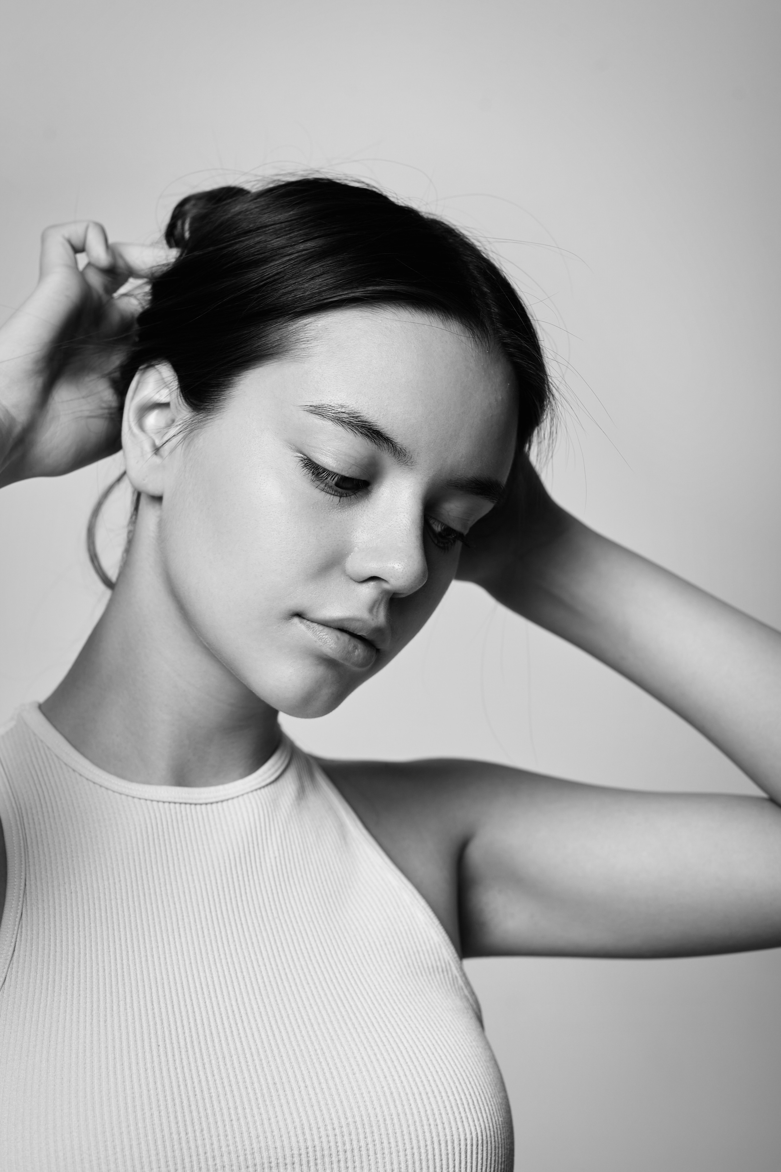 Темноволосая модель Амина в светлых нарядах на фоне светлого фона в студии.