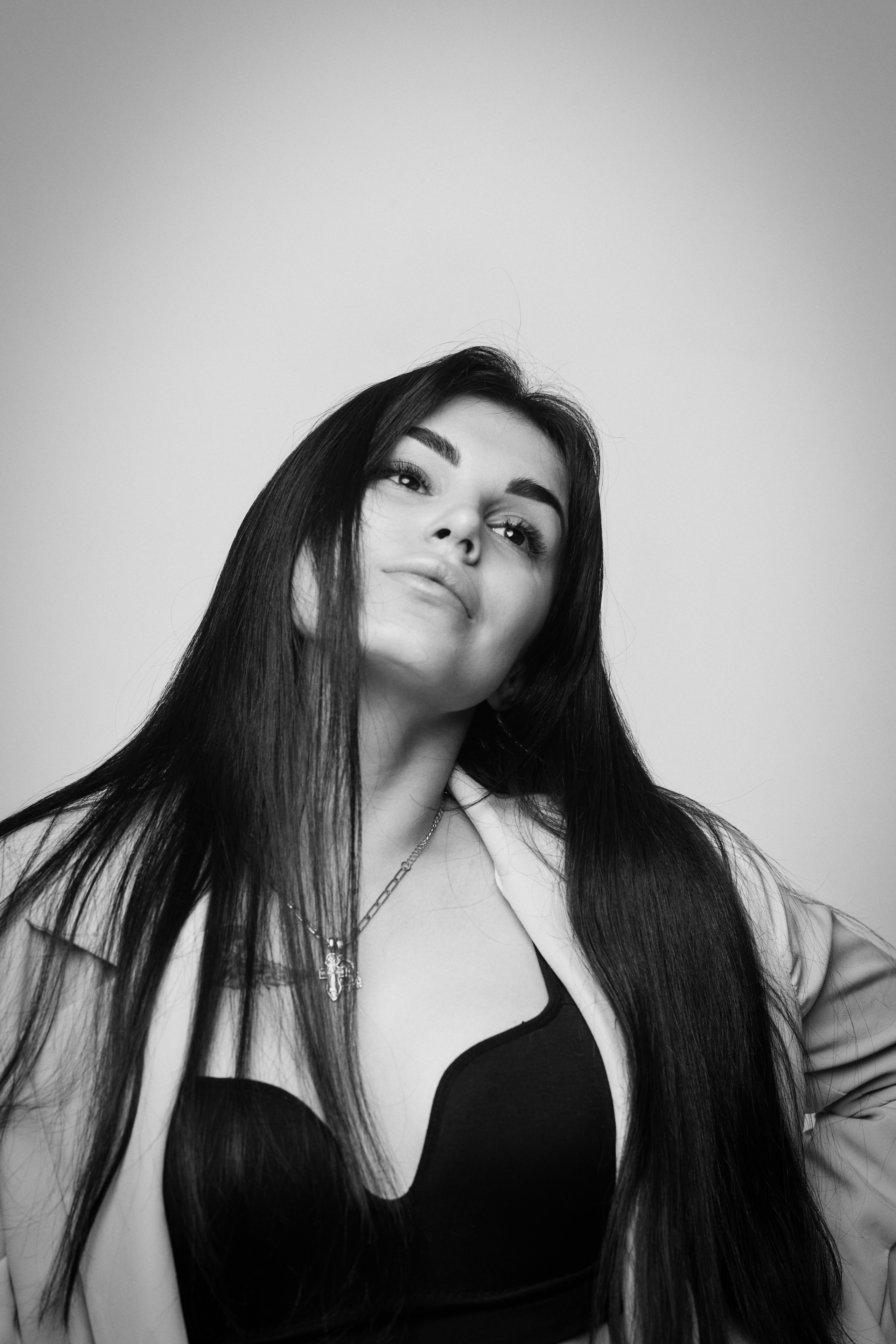 Темноволосая модель Карина в рубашке на светлом фоне студии выглядит легкой и непринужденной, словно готова на все приключения.