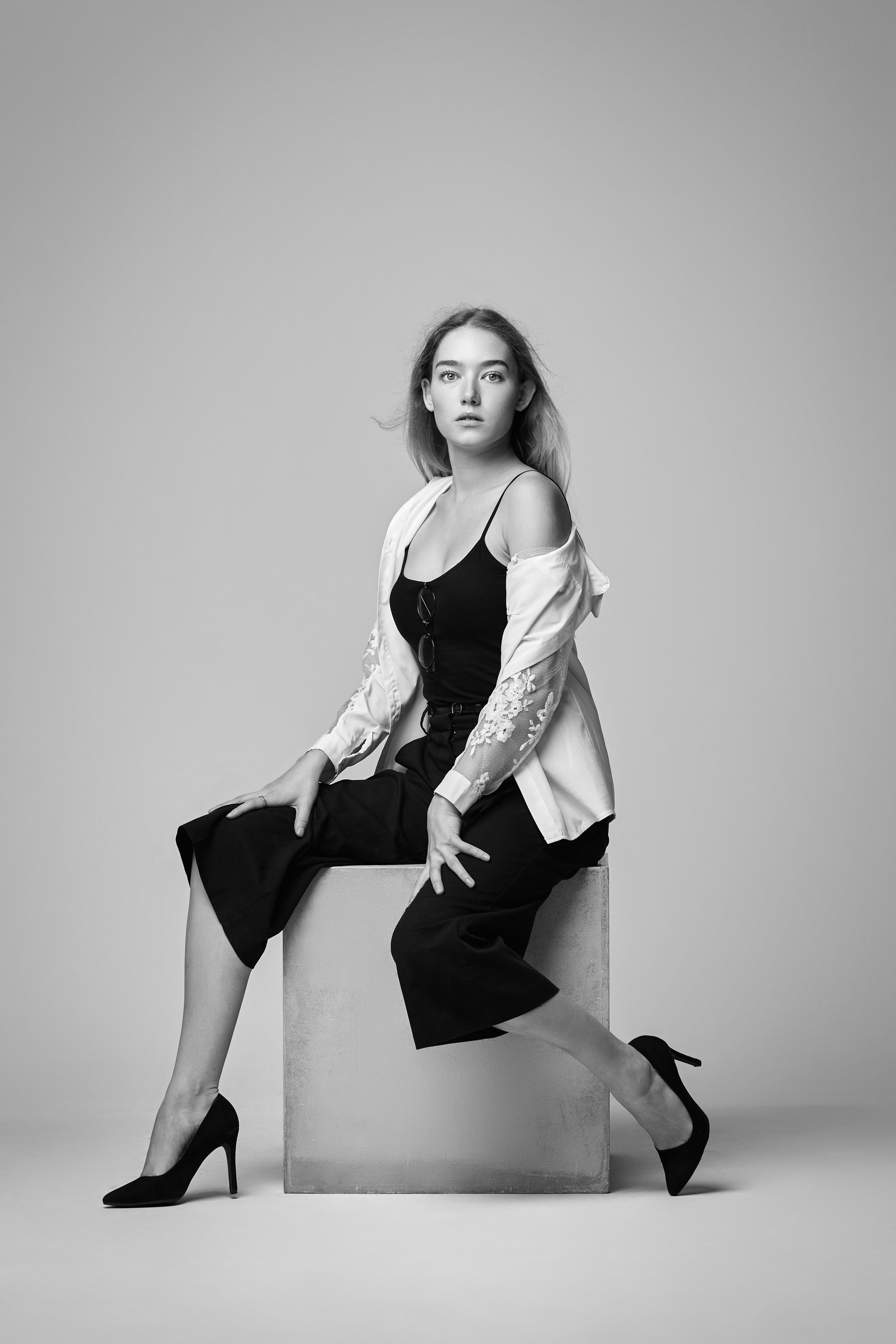 Светловолосая модель на светлом фоне в голубой рубашке и джинсах с высокой посадкой.