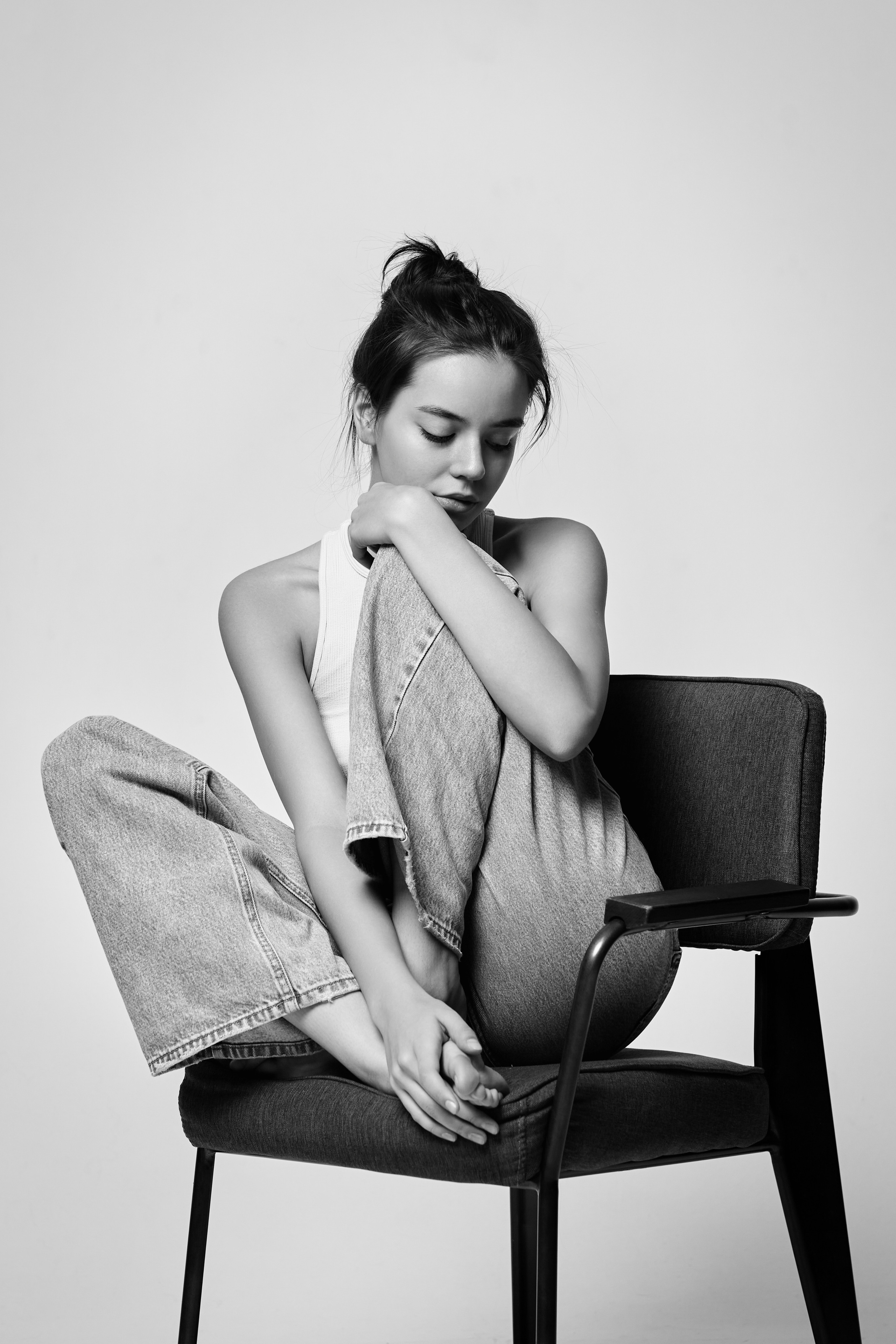 Темноволосая девушка Амина в светлом платье или рубашке на фоне студии.