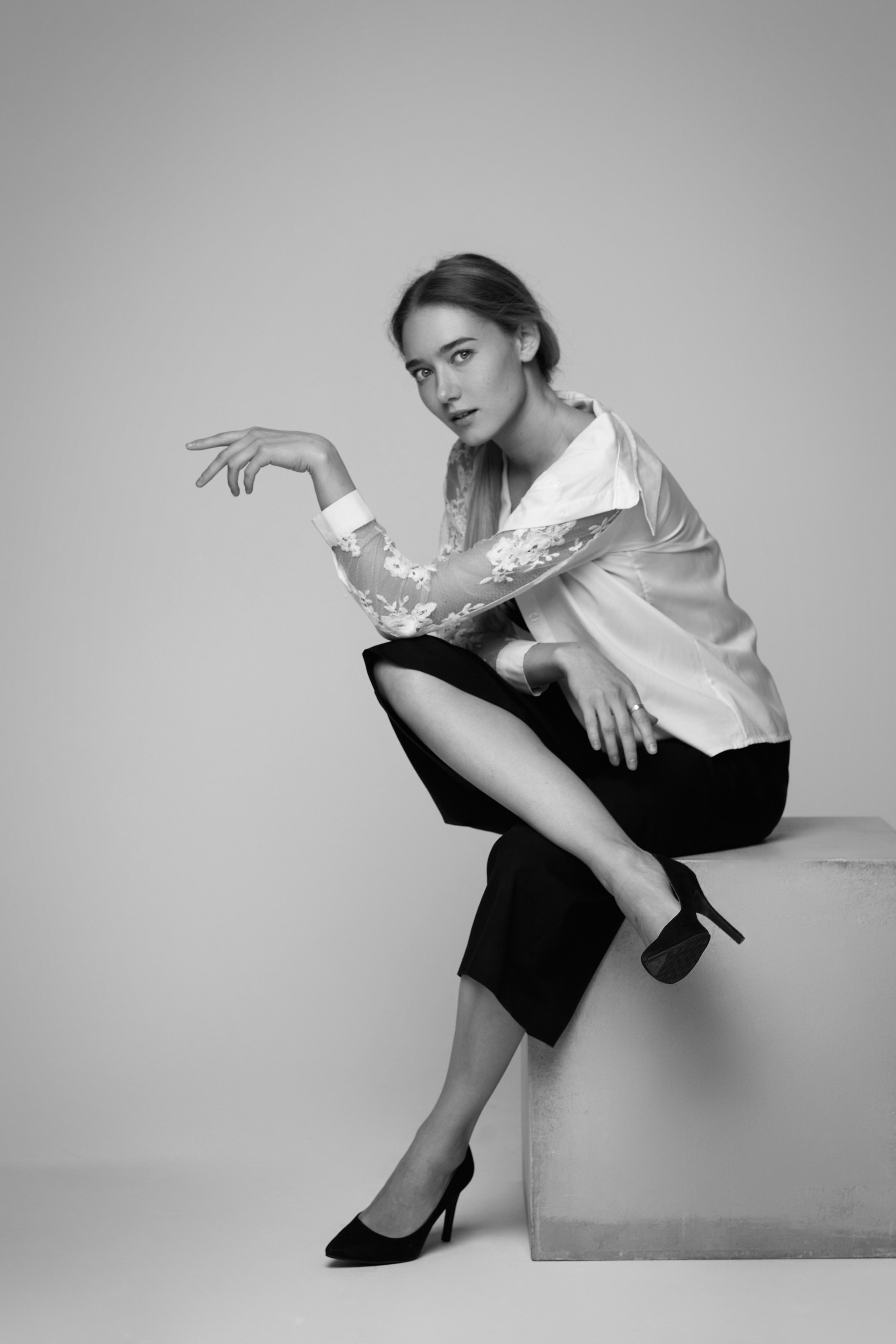 Портрет светловолосой модели Алисы в студии на светлом фоне, позирующей в рубашке и джинсах, с красными губами.