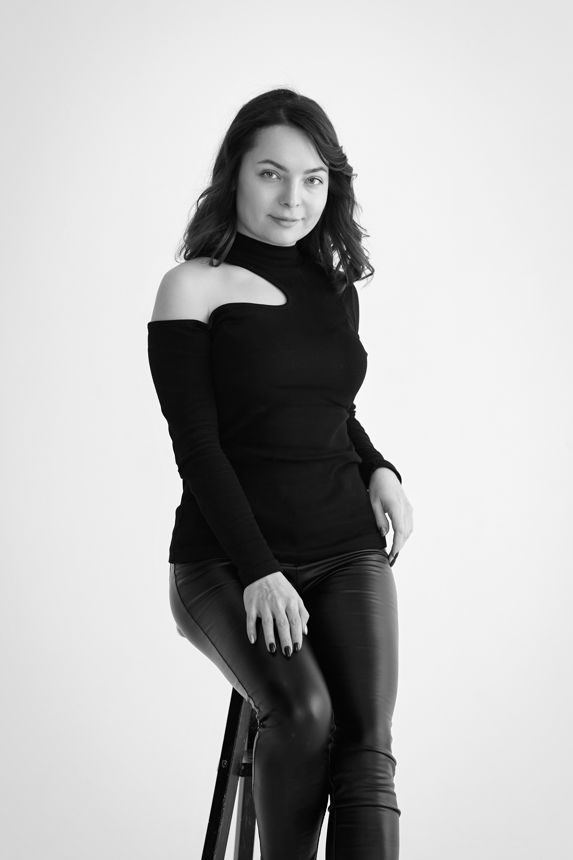 На стуле в студии на светлом фоне сидит модель Татьяна в светлом платье.