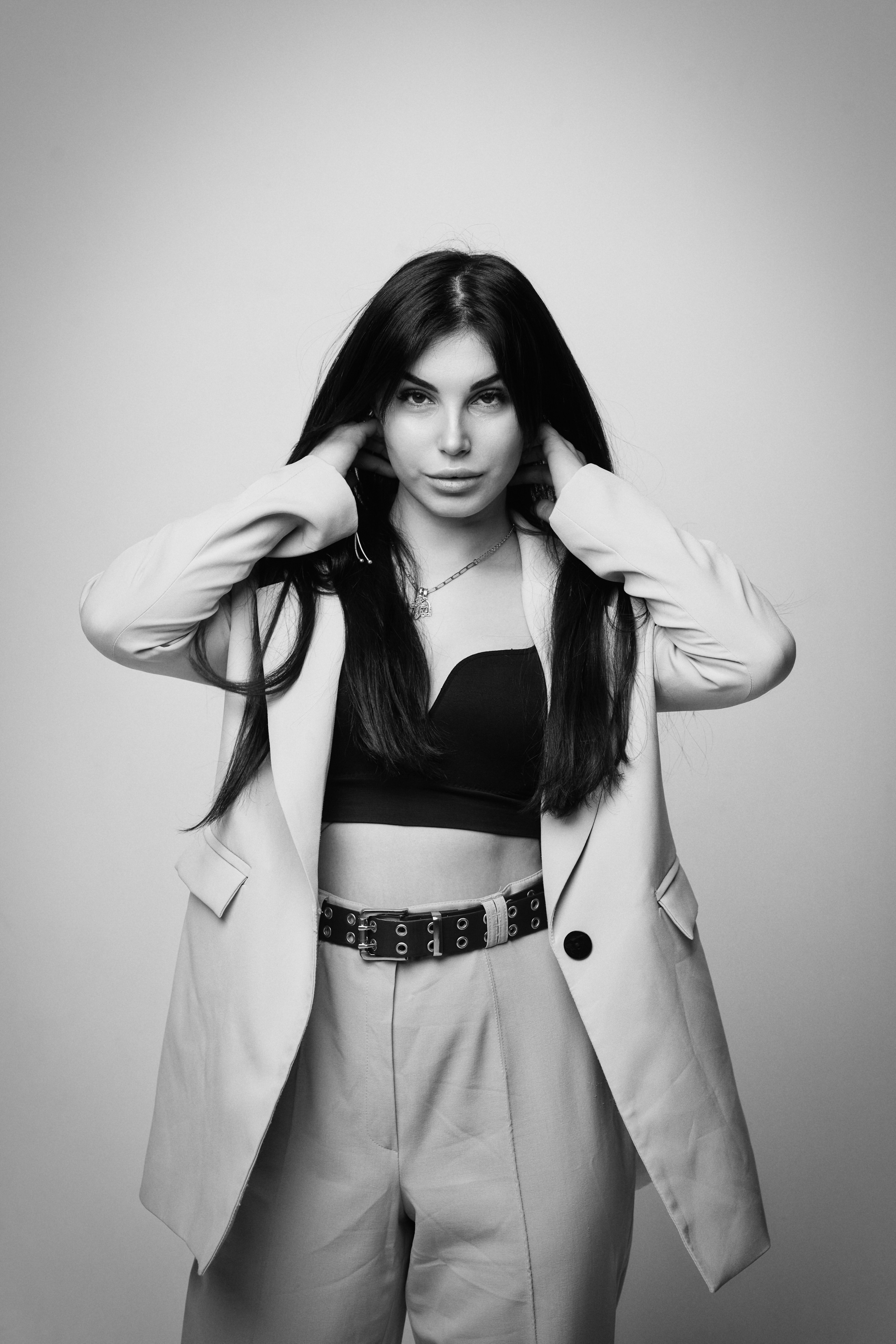 В платье на светлом фоне студии темноволосая модель Карина позирует с неподдельной улыбкой, раскрывая свою натуральность.