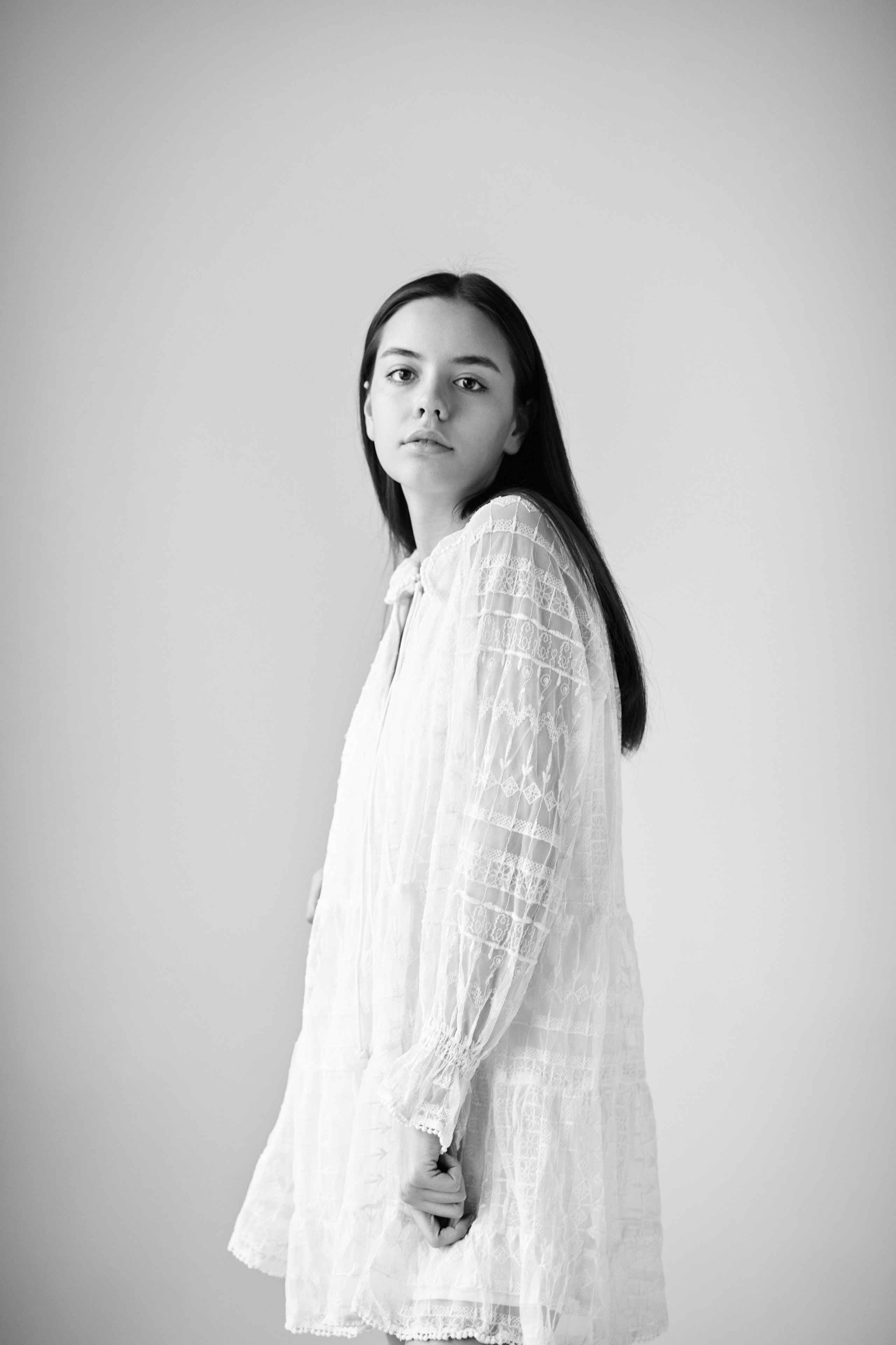 Прекрасная темноволосая девушка Амина в светлом платье на светлом фоне.