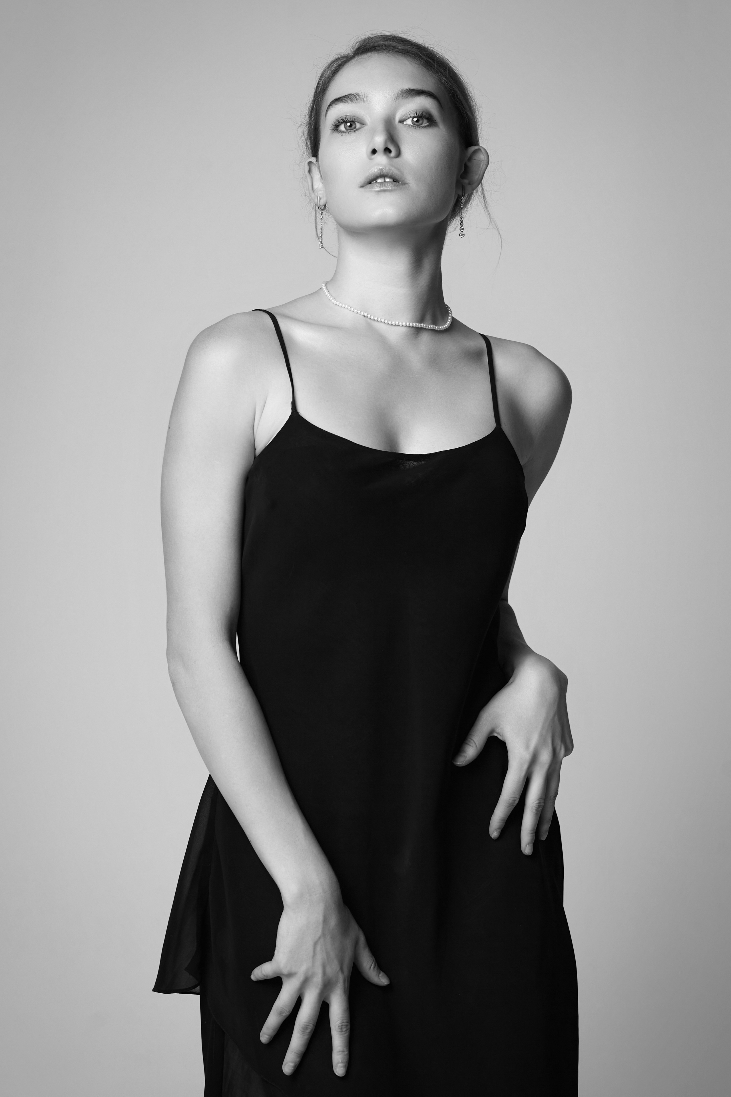 Алиса, светловолосая модель, предстаёт перед камерой в студии на светлом фоне в платье или рубашке.