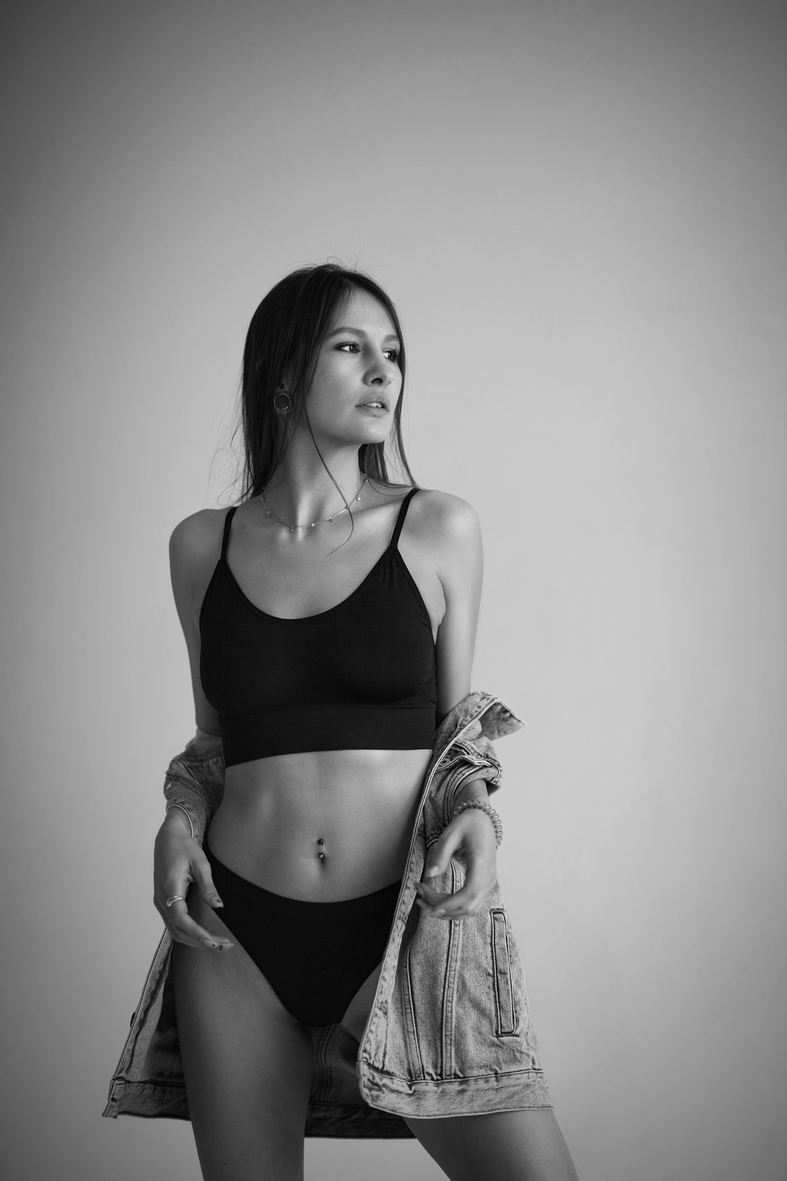 Красивая девушка с темными волосами на темном фоне циклорамы делает привлекательные позы.