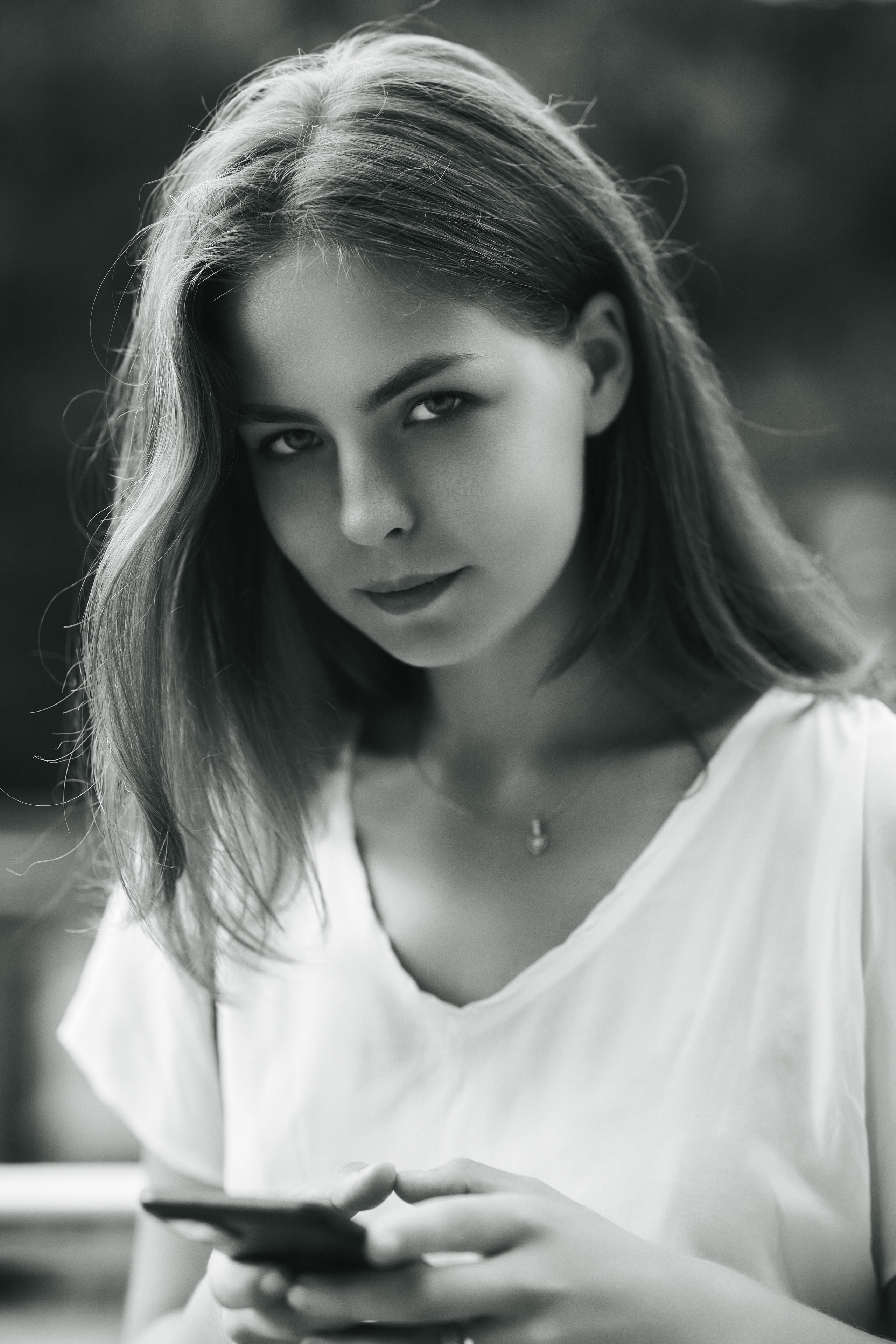 Дарья на фоне города с густыми темными волосами и в светлой кофте