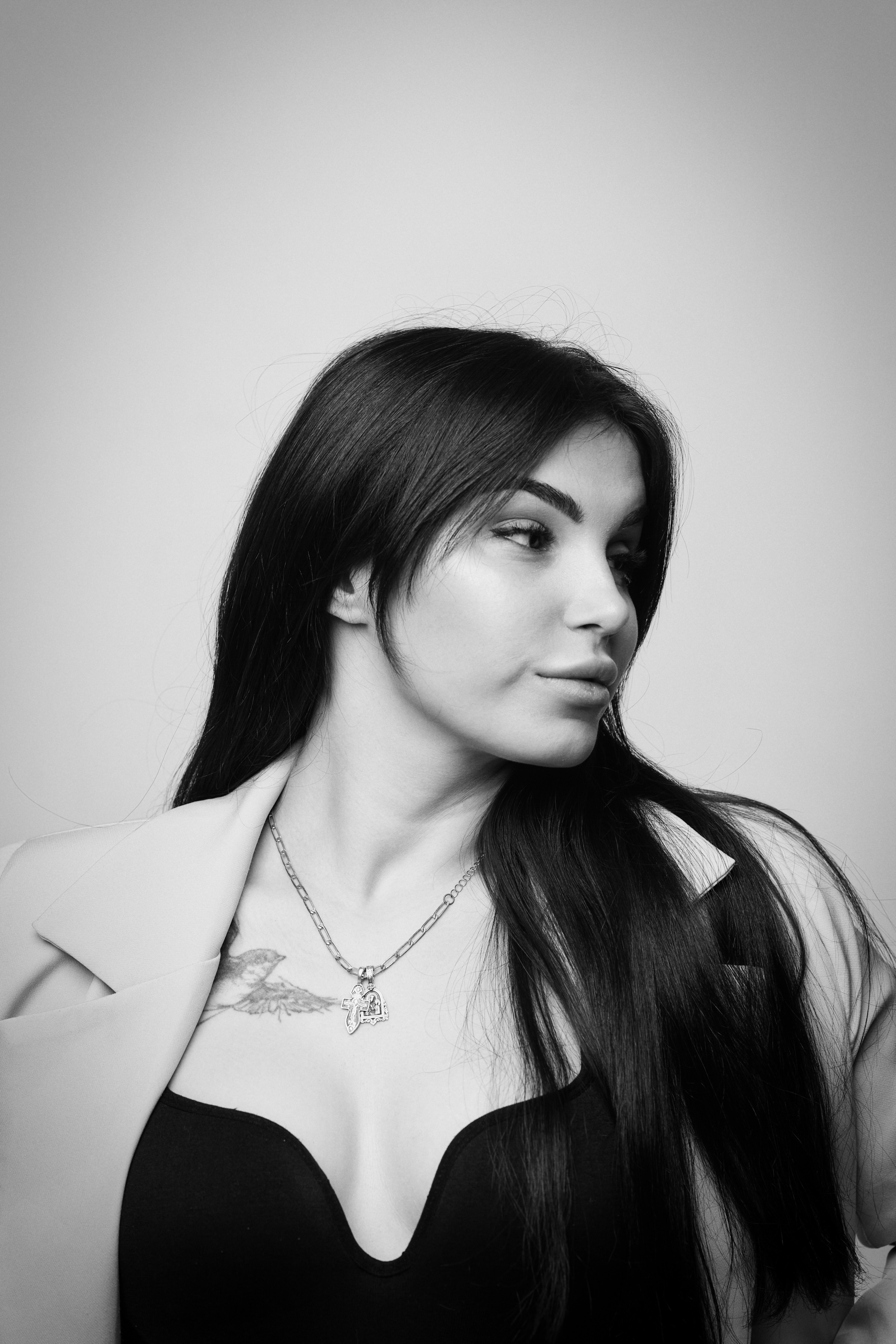 Модель Карина в рубашке на светлом фоне, гармонично сочетающейся с ее темными волосами.