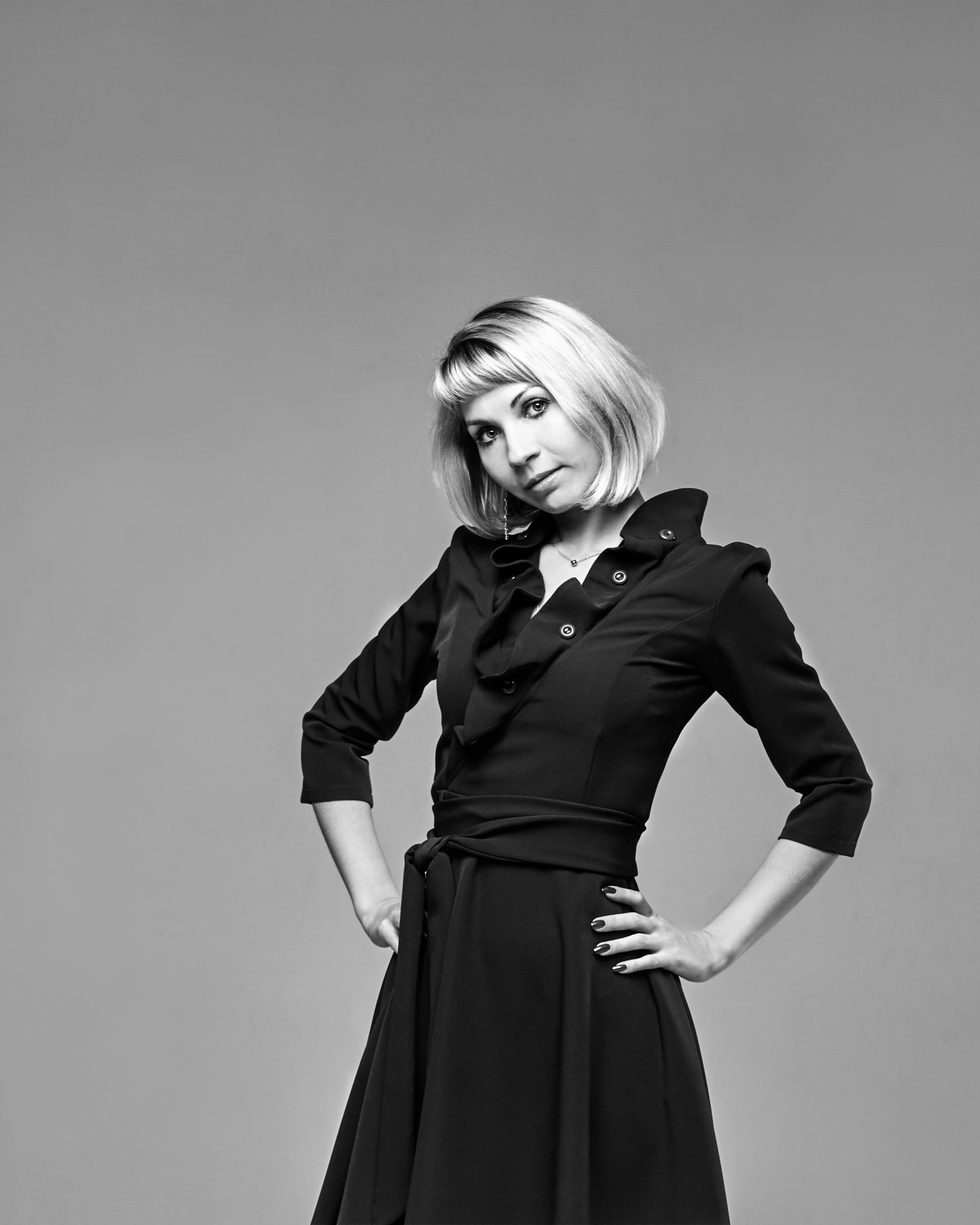 Модель Анастасия с светлыми волосами в платье на темном фоне студии