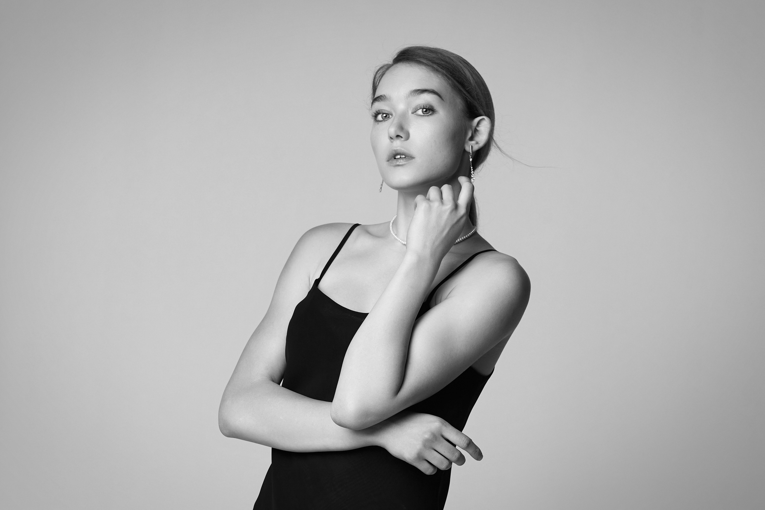 Алиса в студии на светлом фоне в широких брюках и белой футболке с оригинальным принтом.