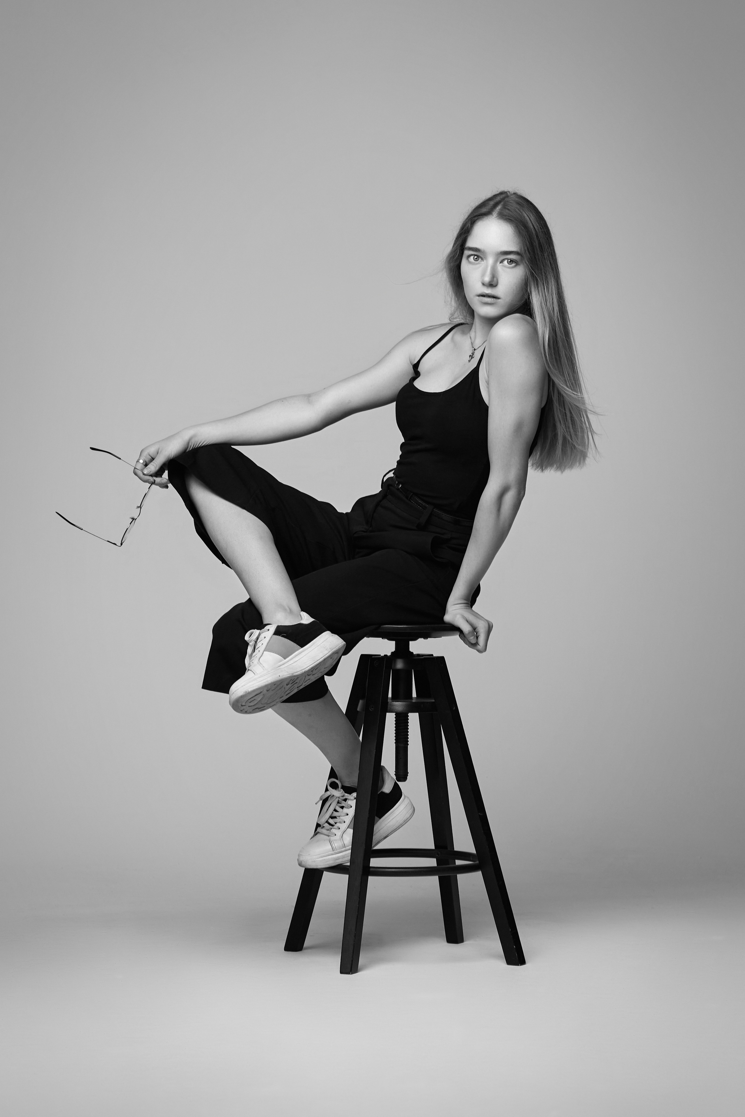 Алиса, известная своими красивыми чертами лица, предстаёт перед камерой в студии на светлом фоне в платье или рубашке.