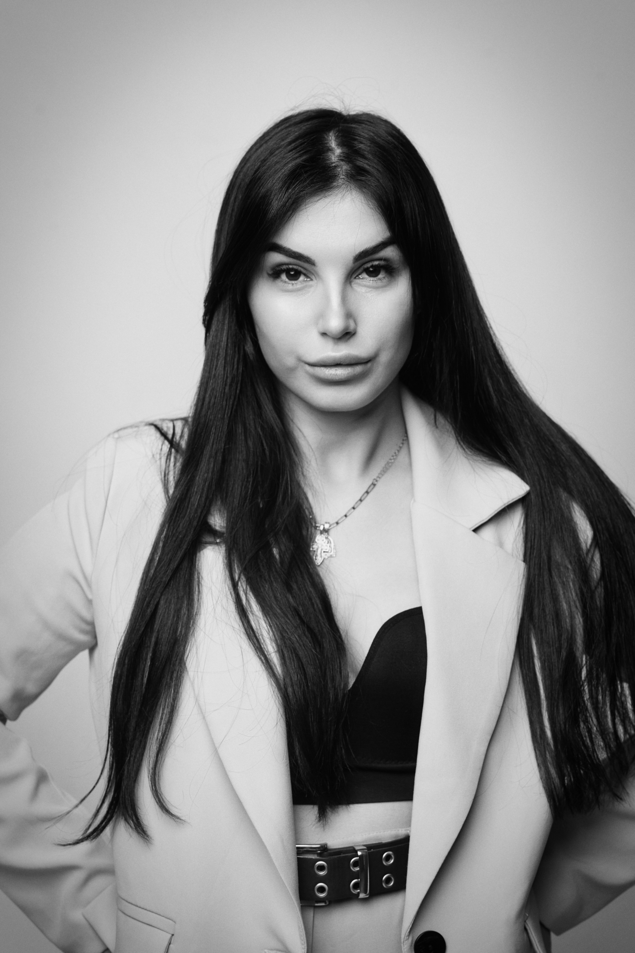 Темноволосая модель Карина в черном костюме на светлом фоне: элегантная фотосессия