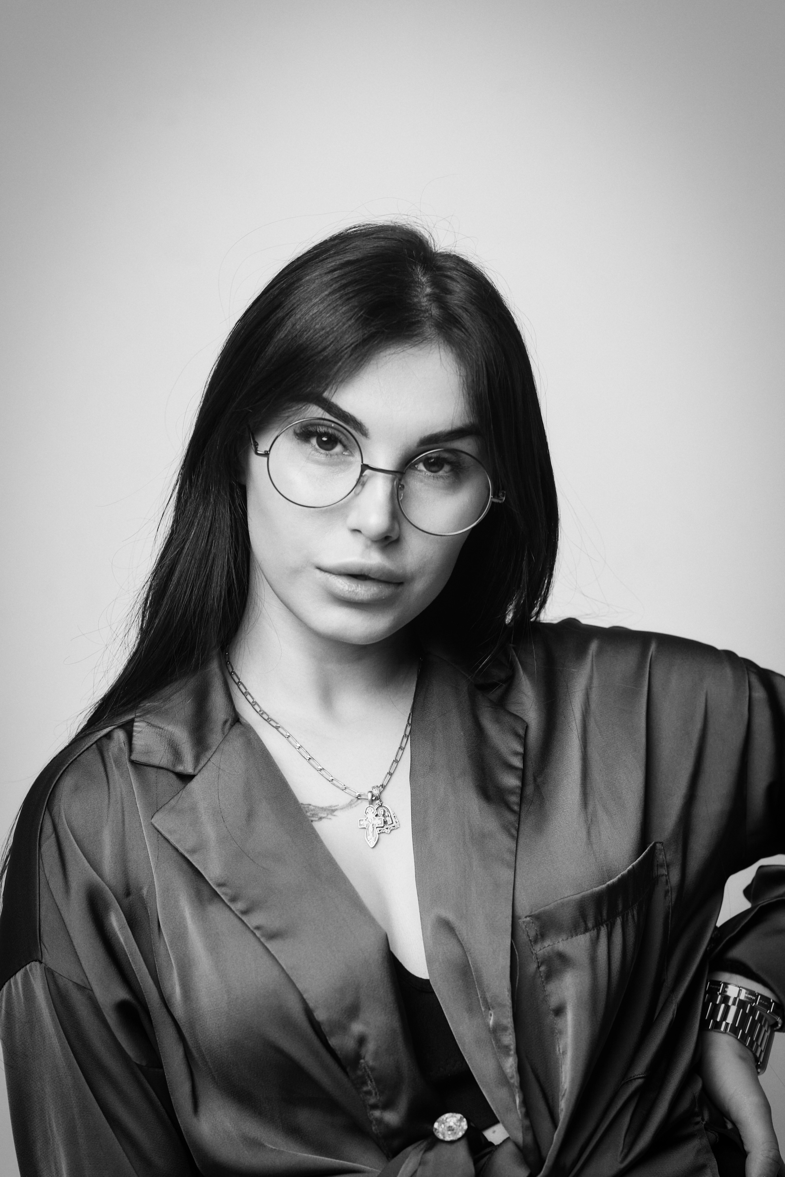 Темноволосая Карина в студии на светлом фоне: уверенная и модная, в платье, рубашке или костюме