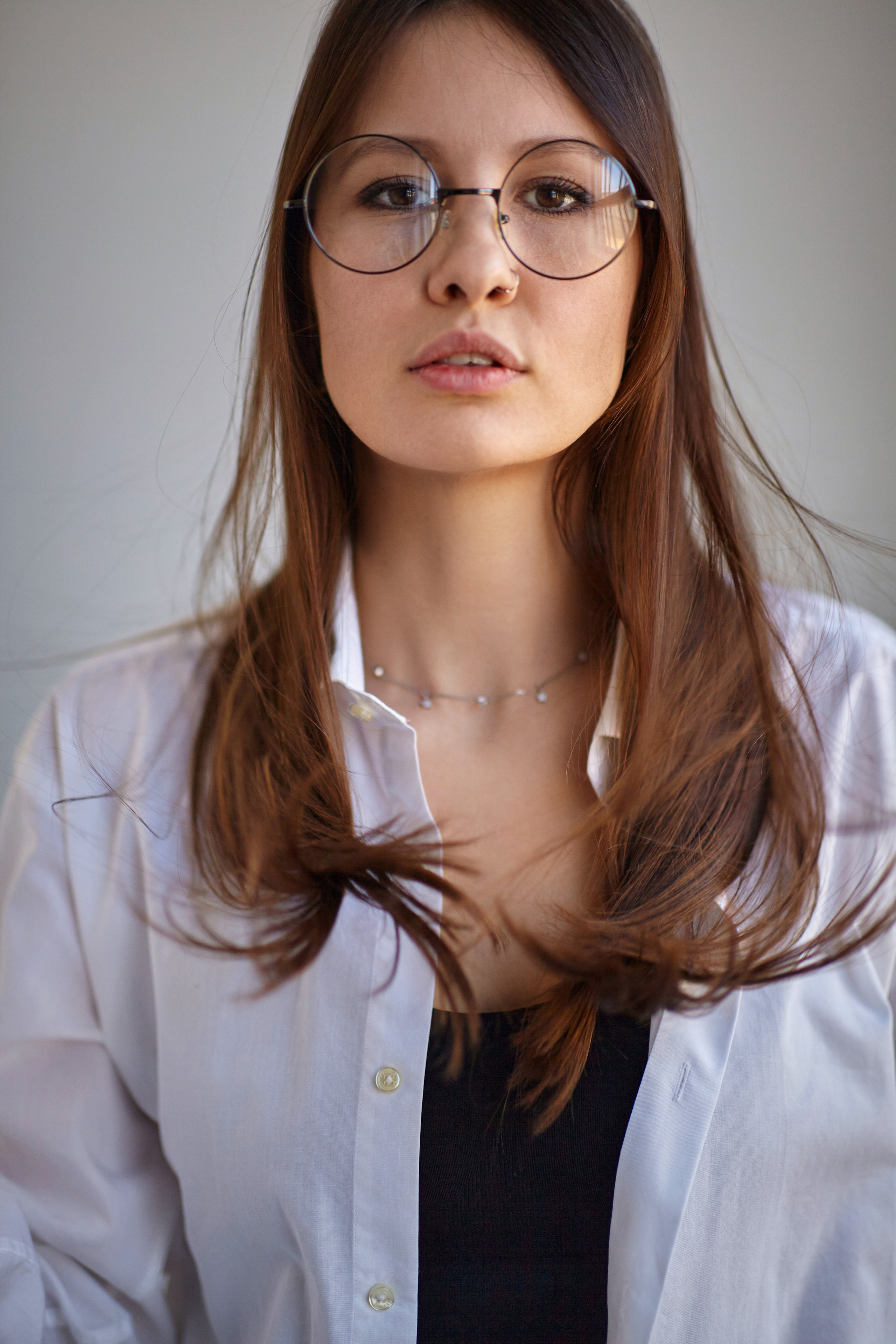 На светлом фоне циклорамы в студии стоит темноволосая красавица.