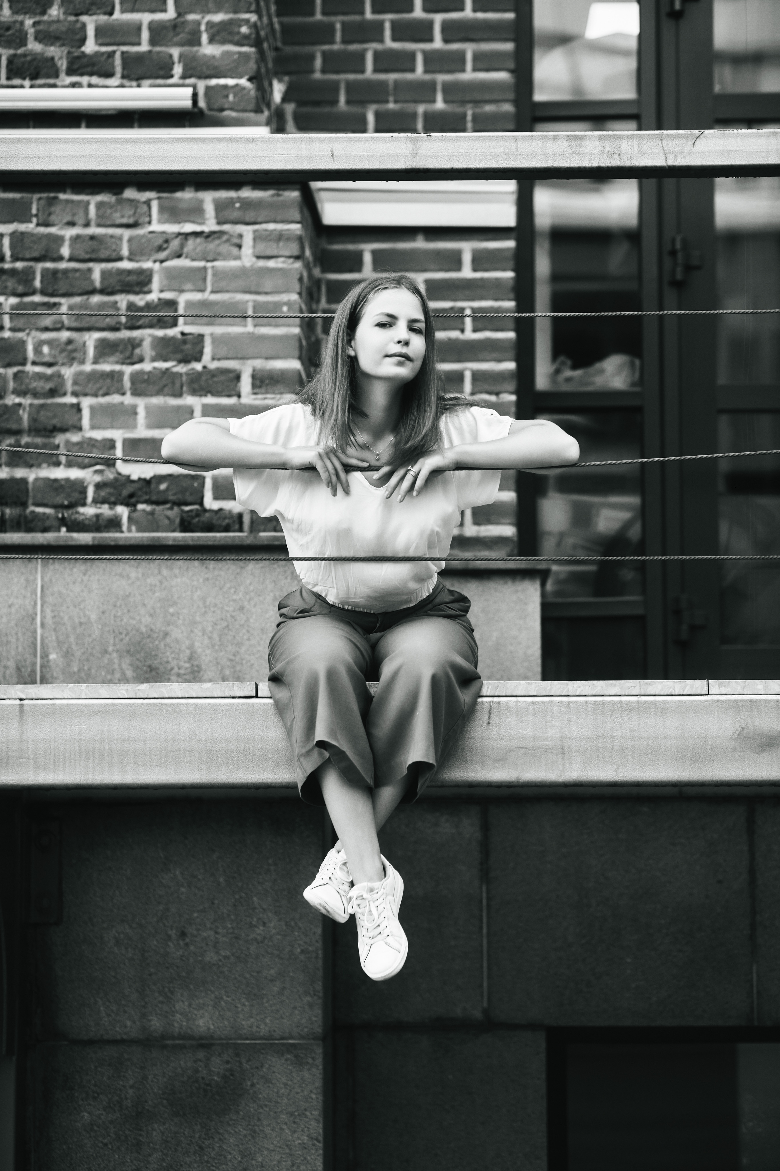 Дарья, одетая в светлую кофту и широкие брюки, позирует на улице Москвы.