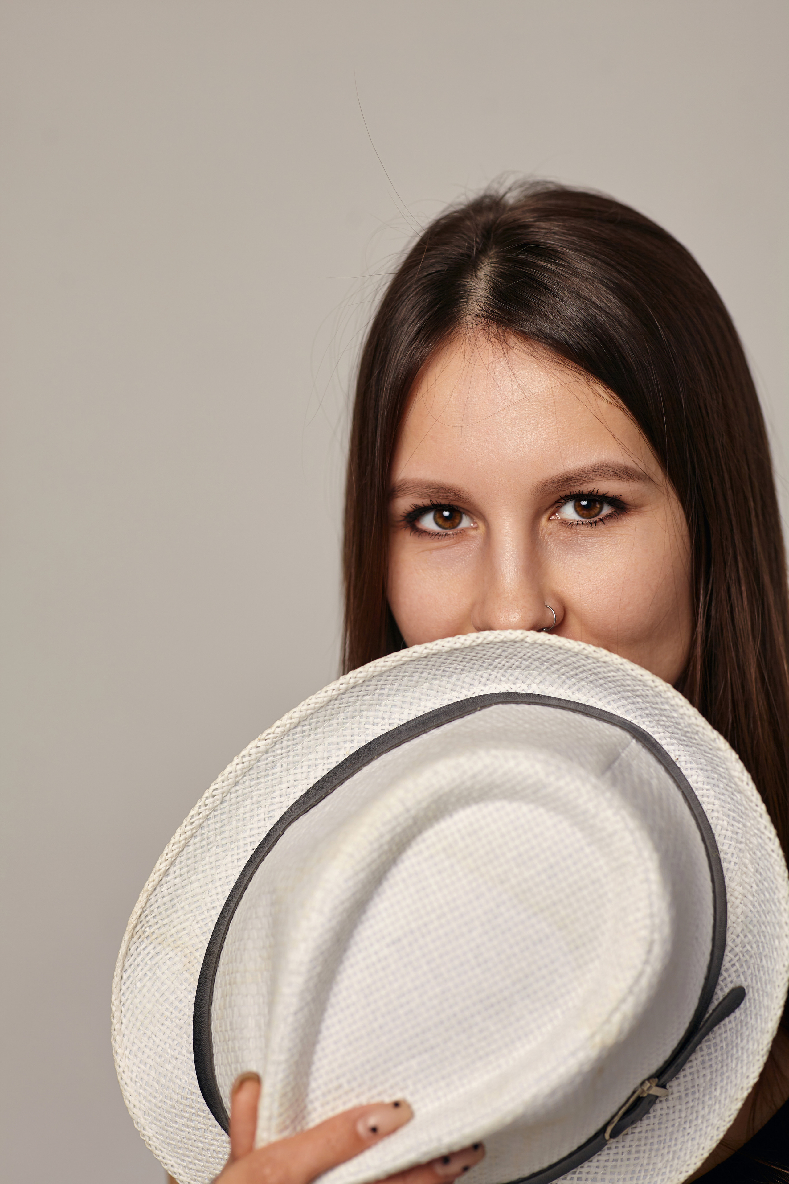 Стильная темноволосая модель в фотостудии на светлом фоне