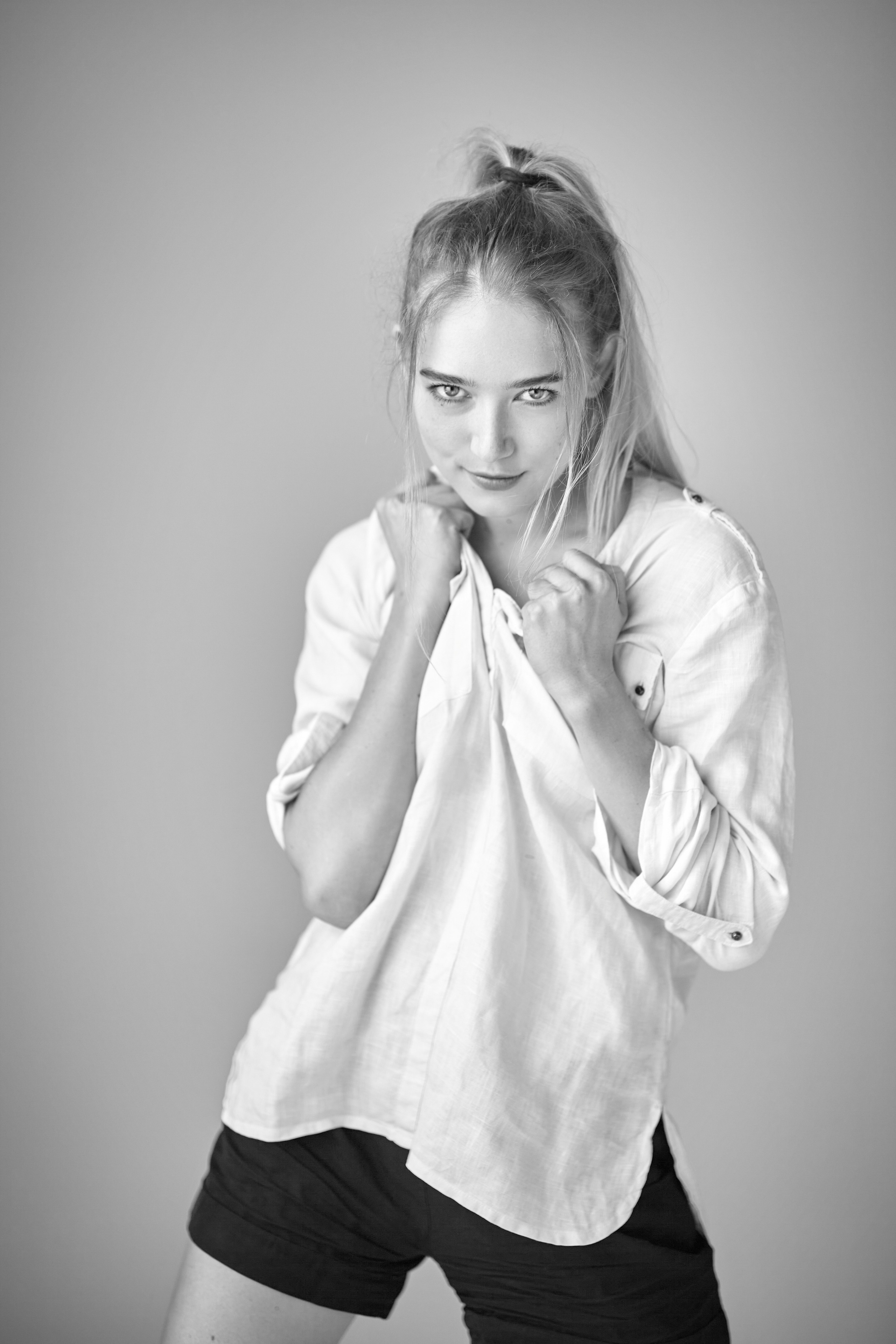 В своём классическом белом платье, светловолосая модель Алиса выглядит изумительно на светлом фоне студии.