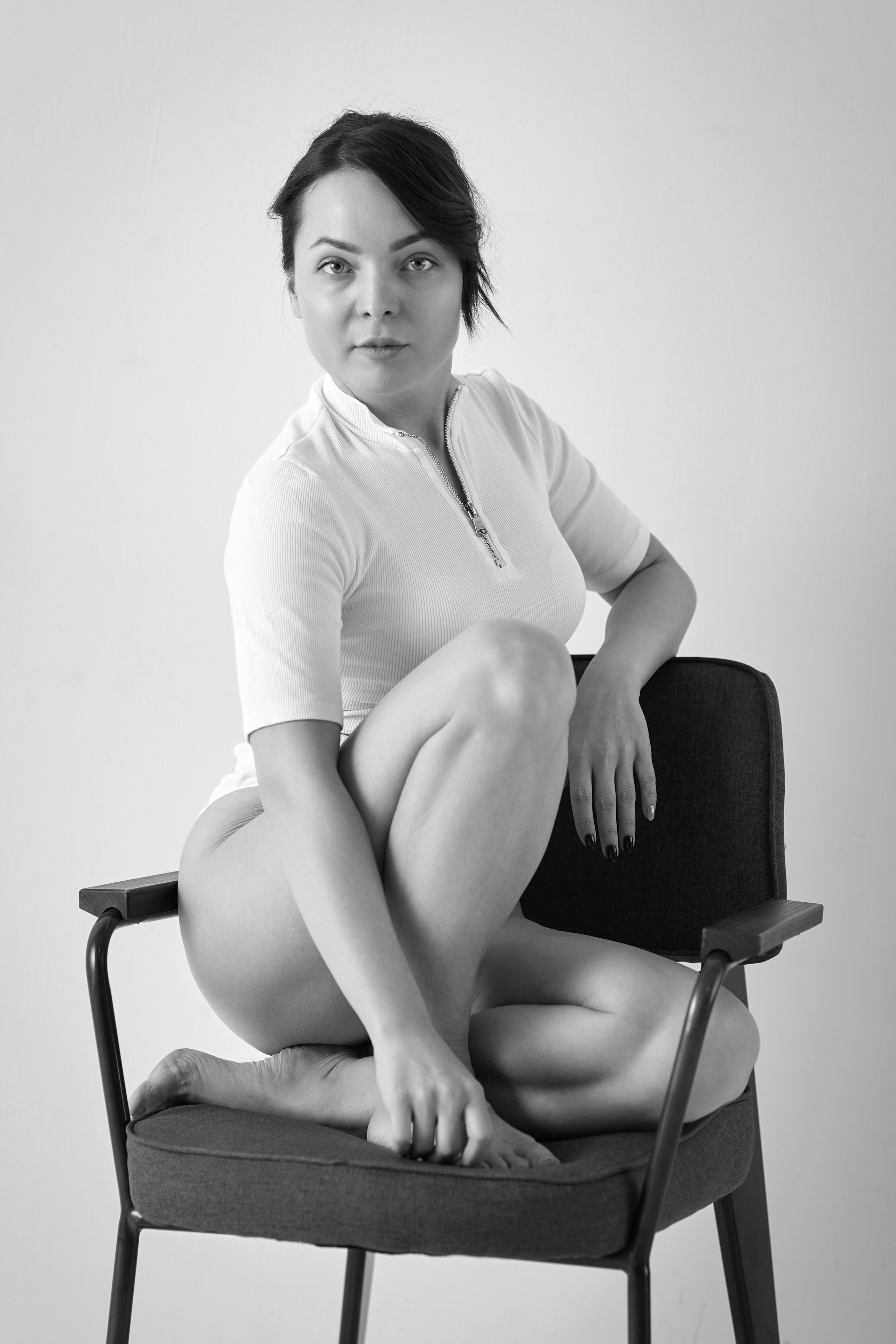 Темноволосая модель Татьяна позирует в светлом платье на фоне светлого фона в студии.